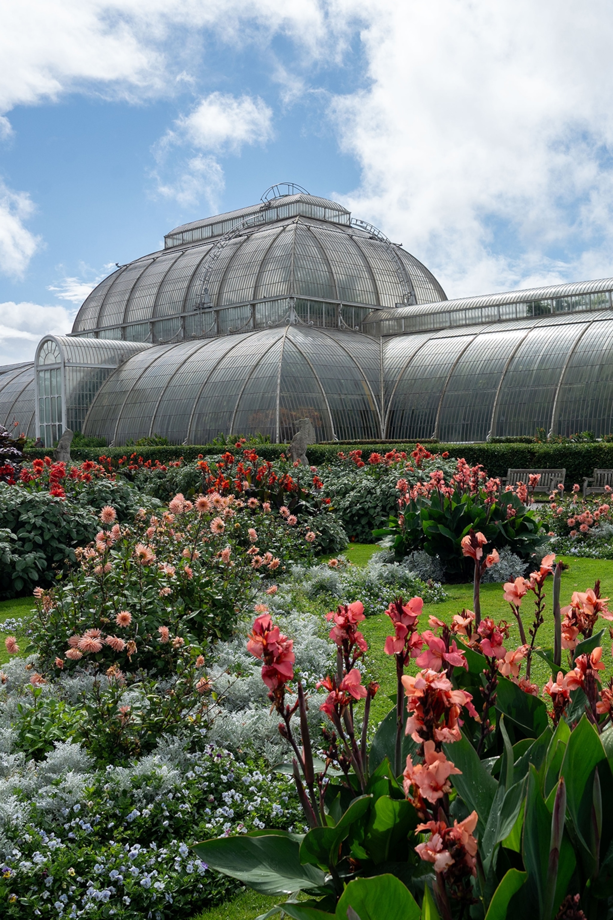 A domed glass greenhouse in a garden with flowers.