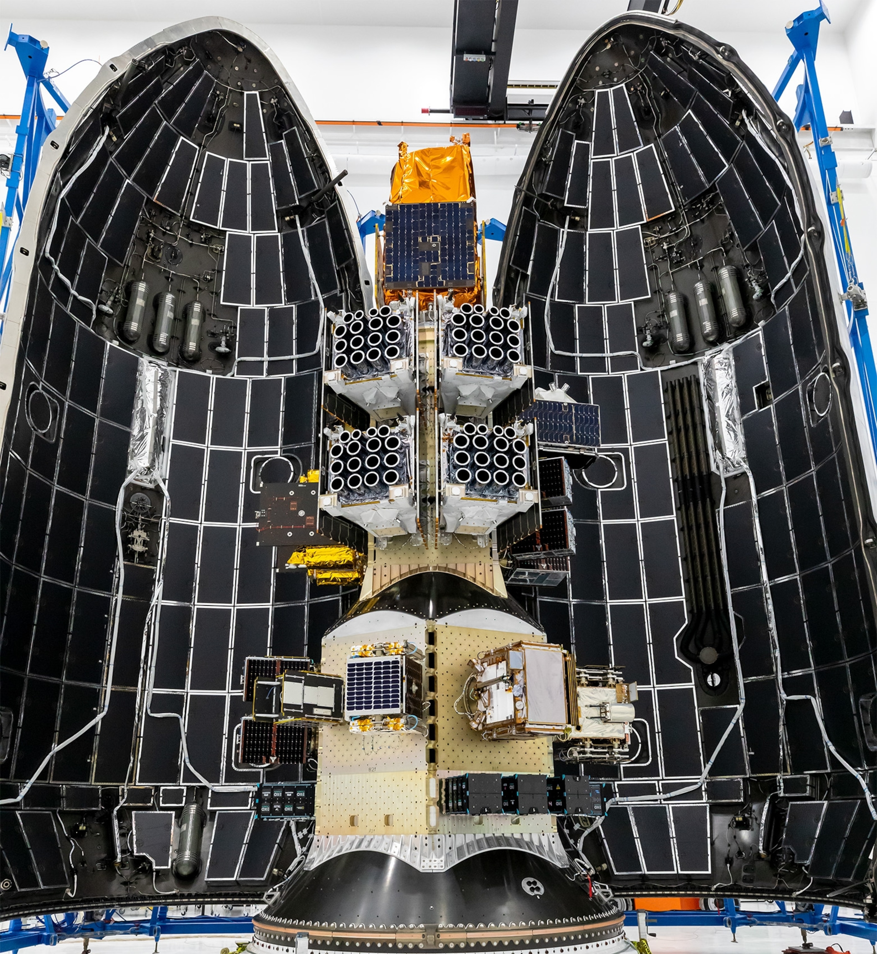 Open rocket fairing reveals its interior filled with intricate satellite clusters and components