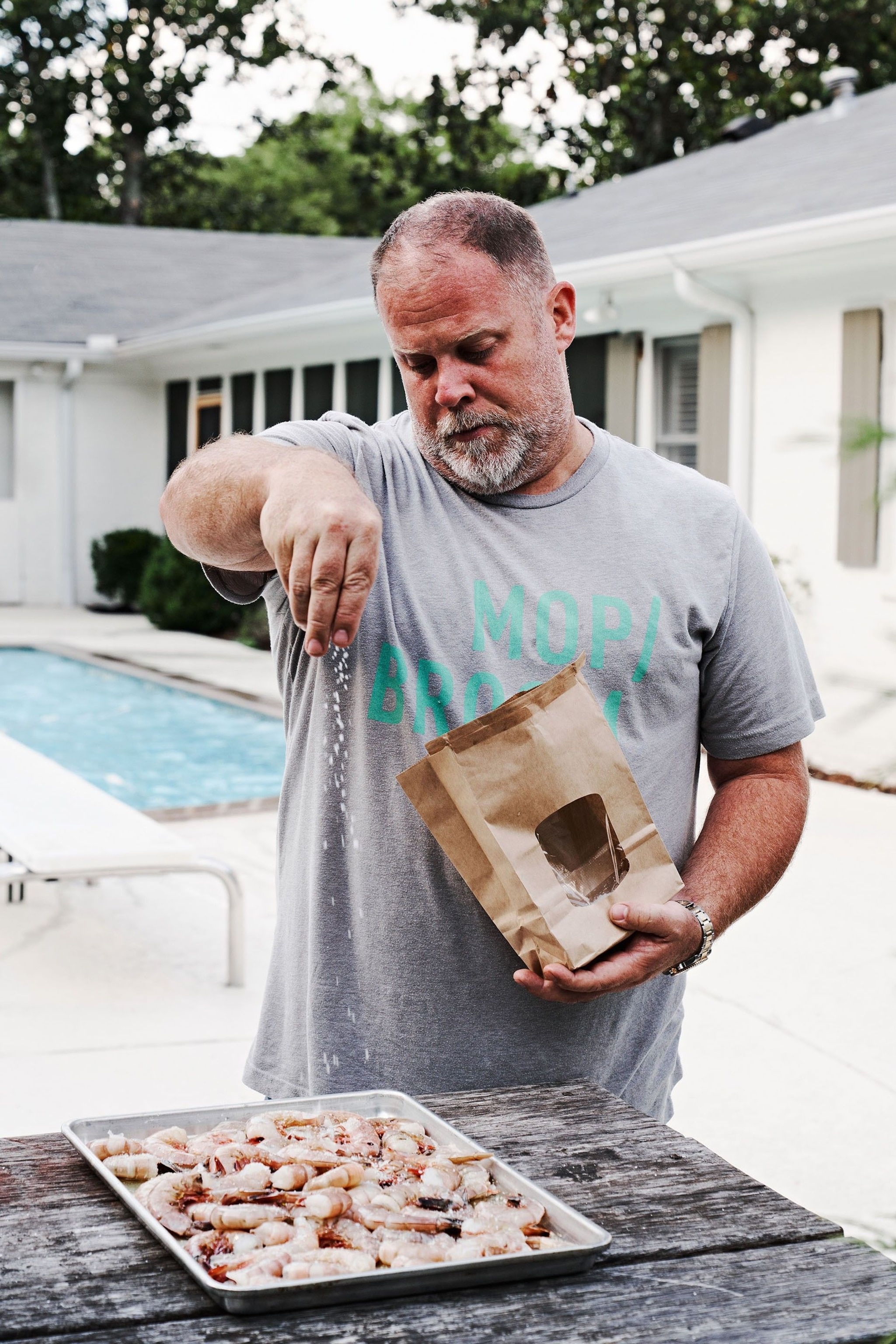 Pat seasoning the Mississippi Gulf shrimp. He sprinkles the whole lot with his own Memphis-style rib rub — a dry mix of brown sugar, salt and pepper, paprika, cayenne, chilli, mustard powder, oregano, garlic powder and onion powder.
