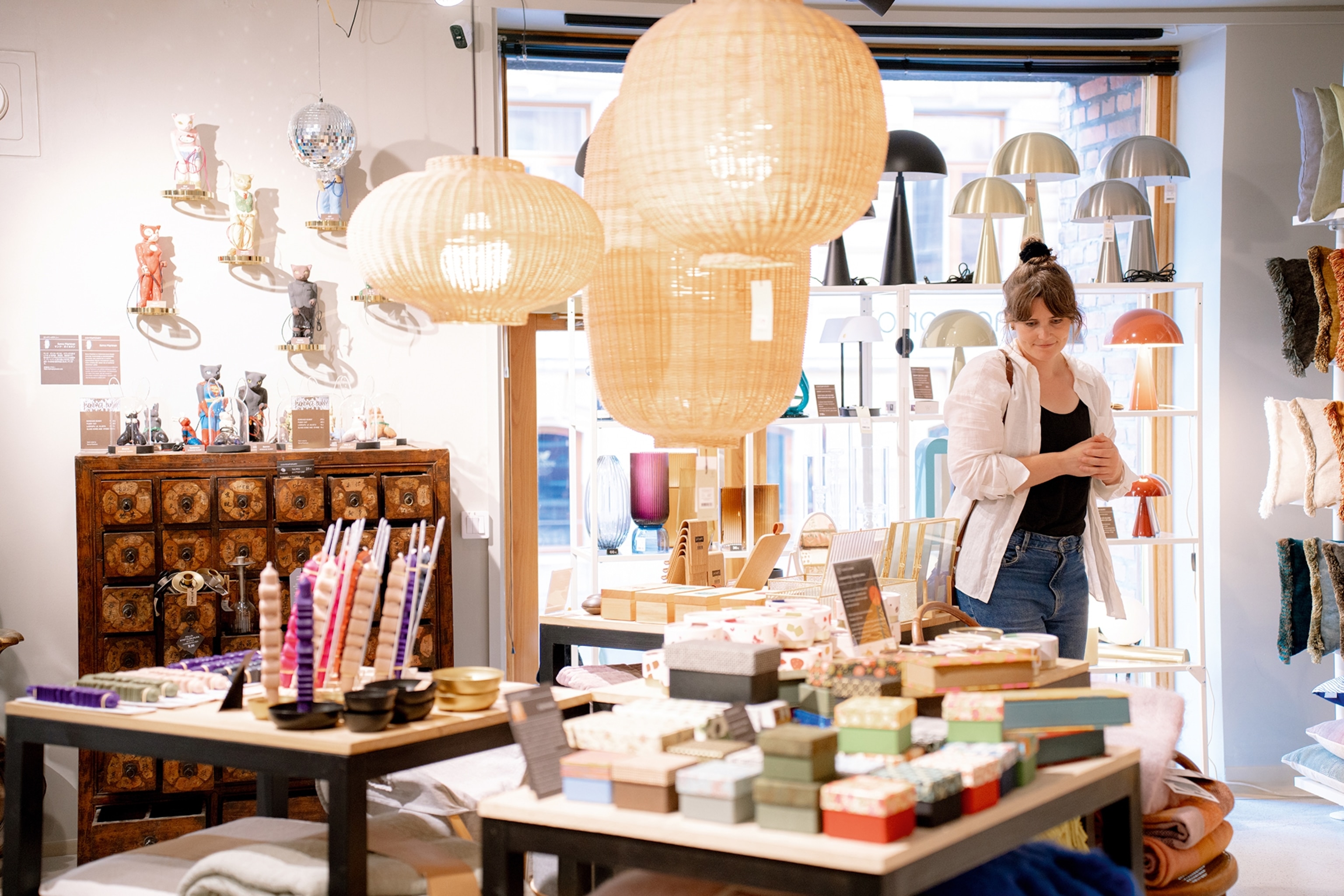 A woman browsing a modern shop selling stationary, glasswear and furniture.