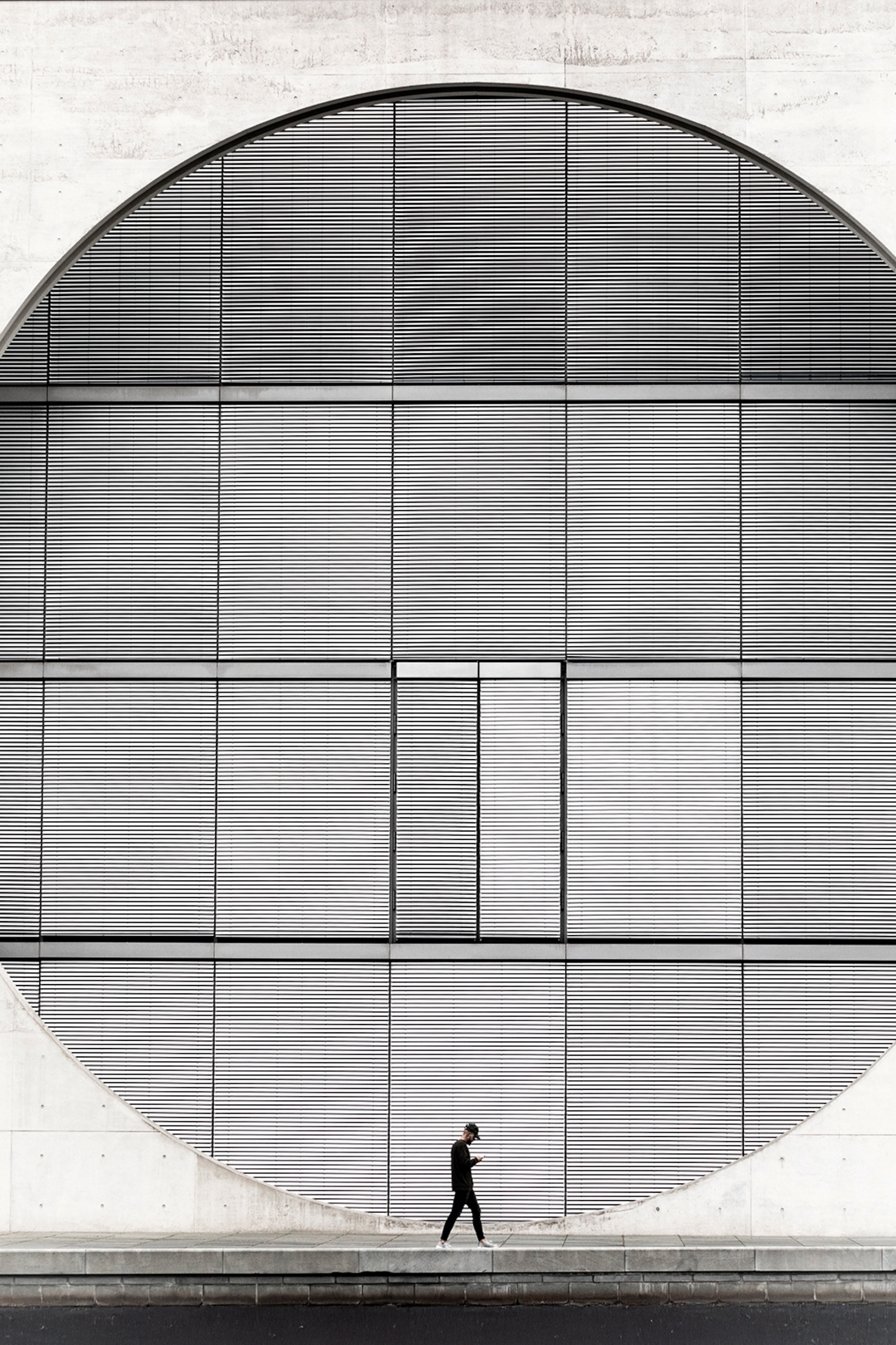 An abstract building façade with vents arranged behind a circle opening in the cement wall.