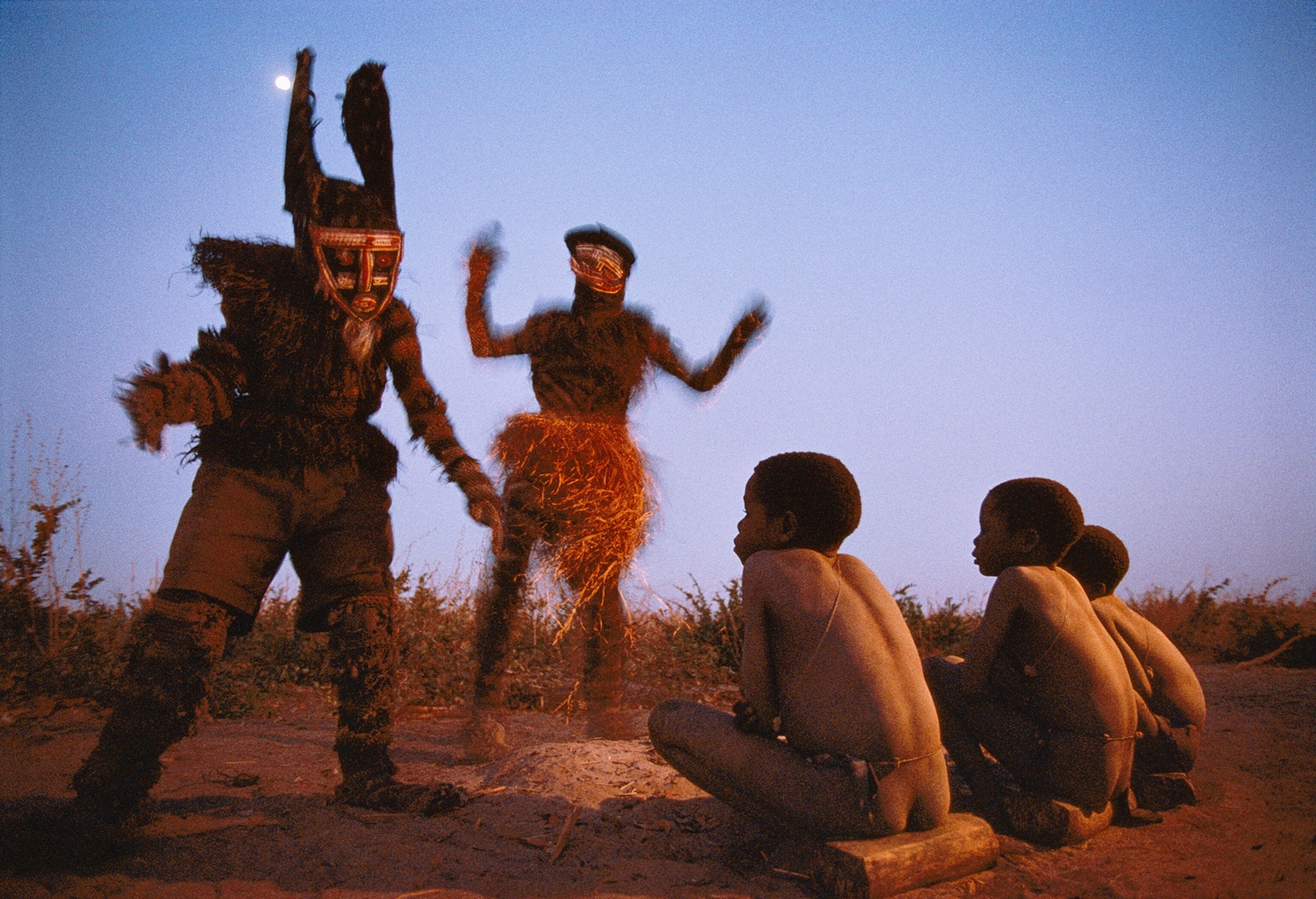 'Makishi' dancers perform before a group of newly circumcised boys.