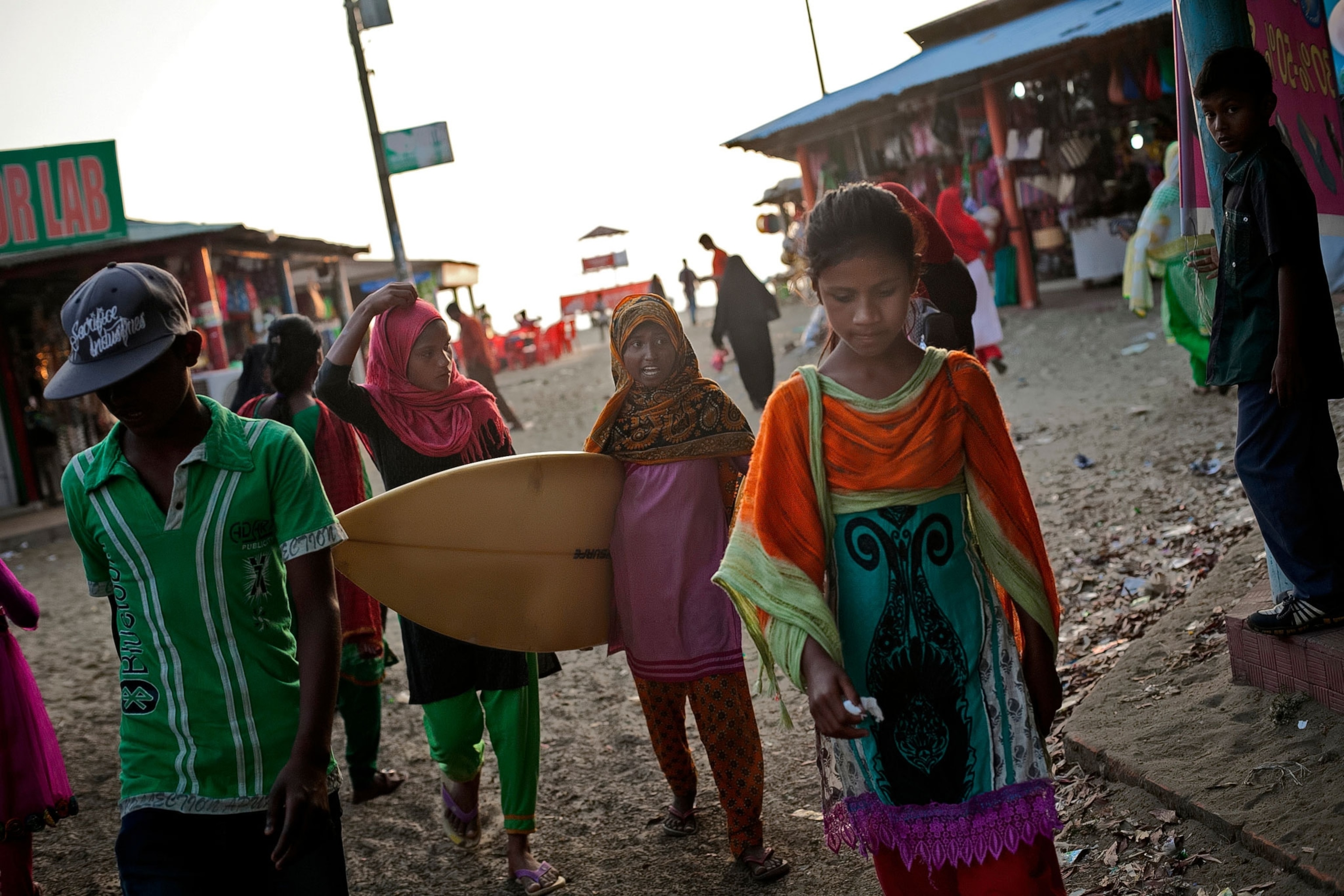 Suma, Johanara, and Shobe Majaraz walk through a market on the beach.