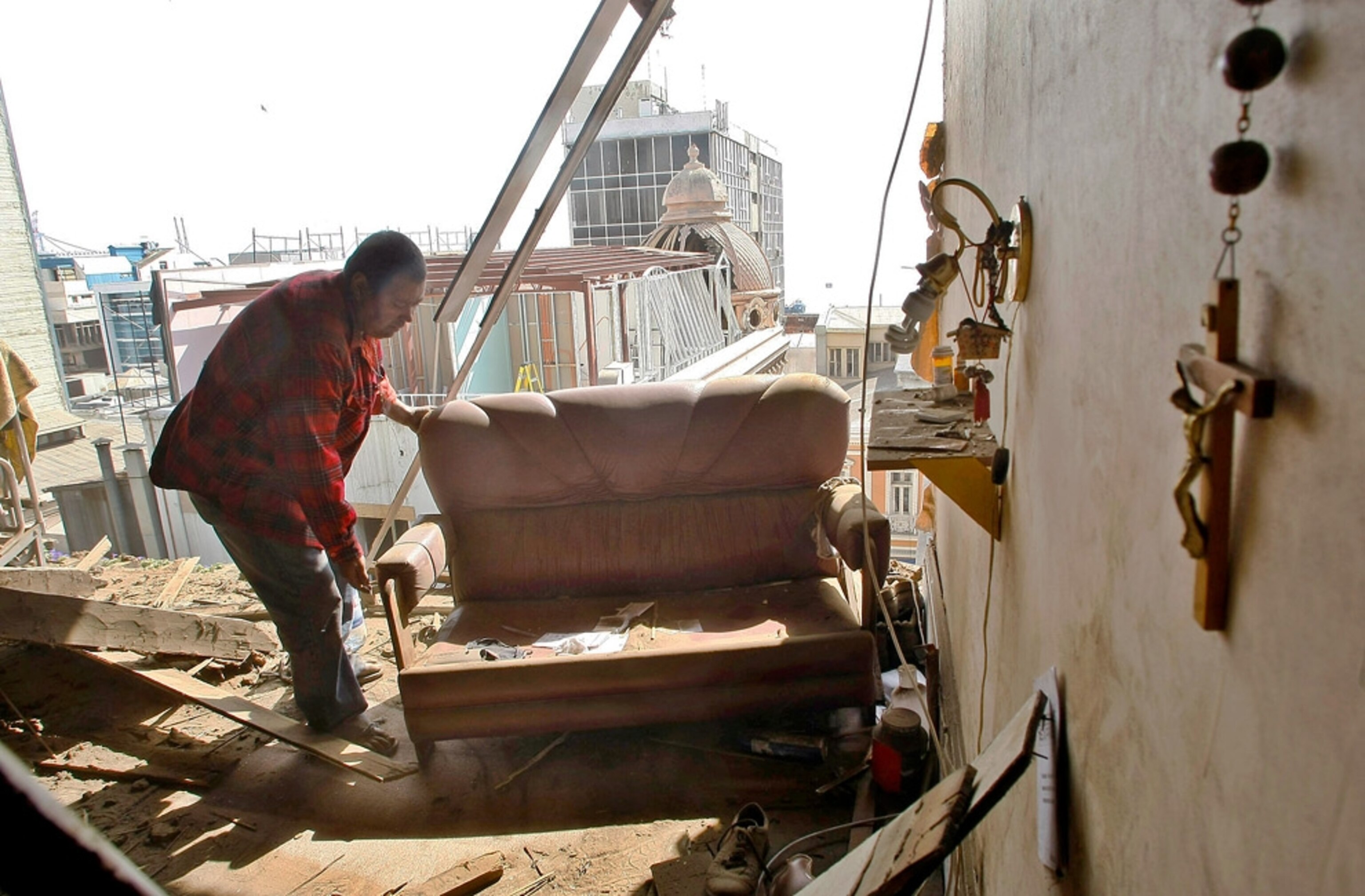A man moves his belongings inside his home destroyed in an earthquake in Valparaiso February 27, 2010.