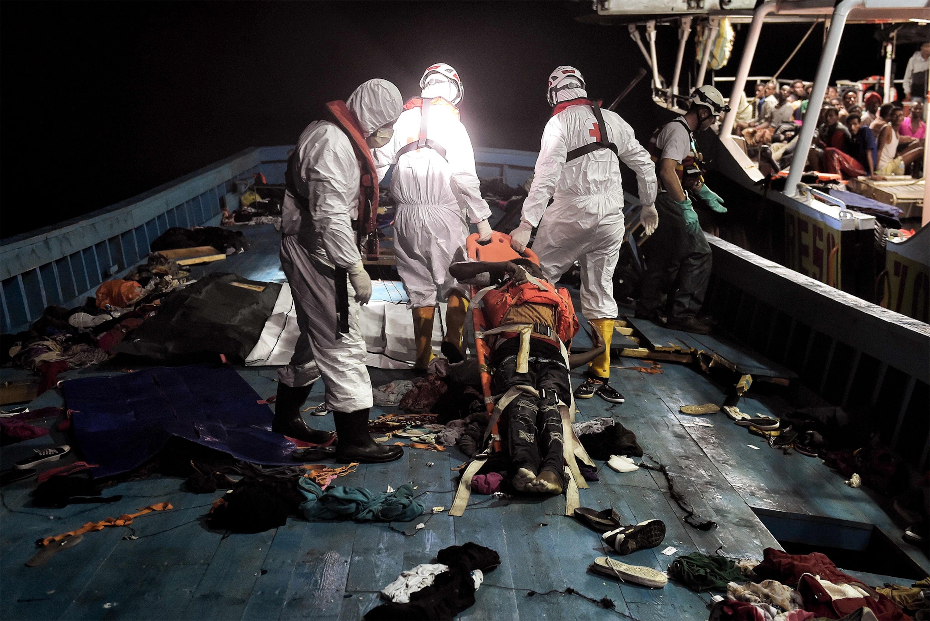 rescue workers carrying a dead body of a migrant off a boat