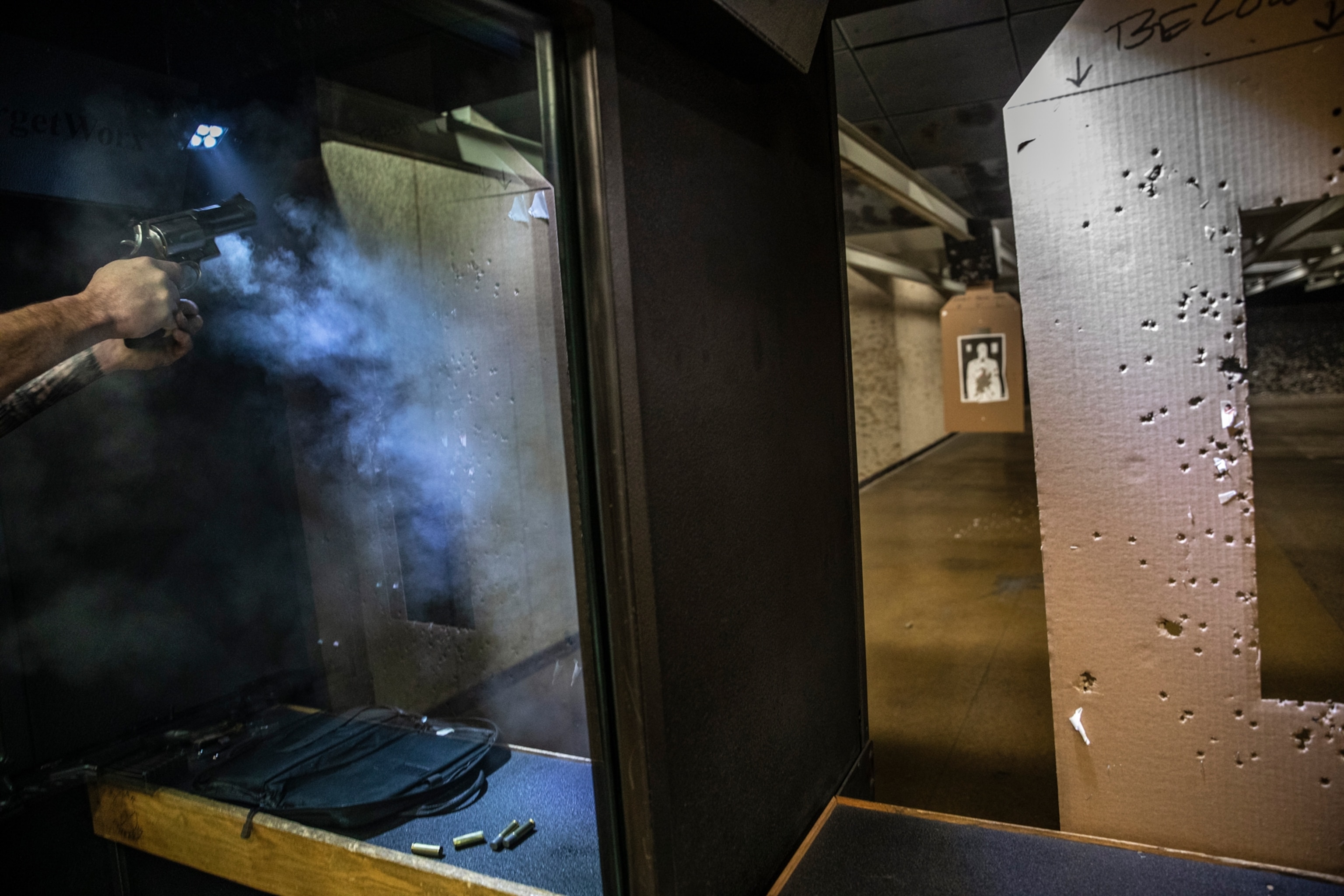 A person firing at a target at a indoor gun range
