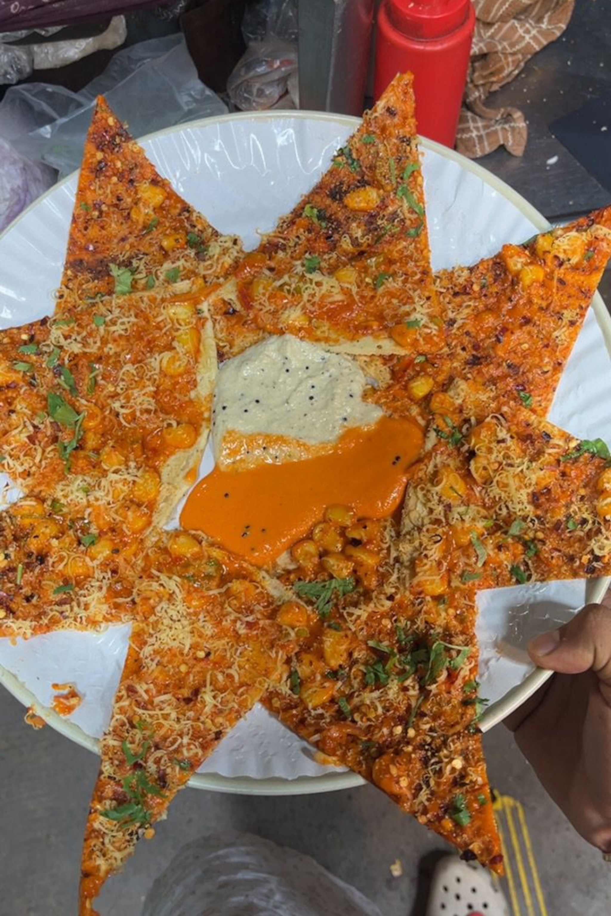 Pizza slices arranged like a star on a plate with two sauces in the middle and chickpea toppings.