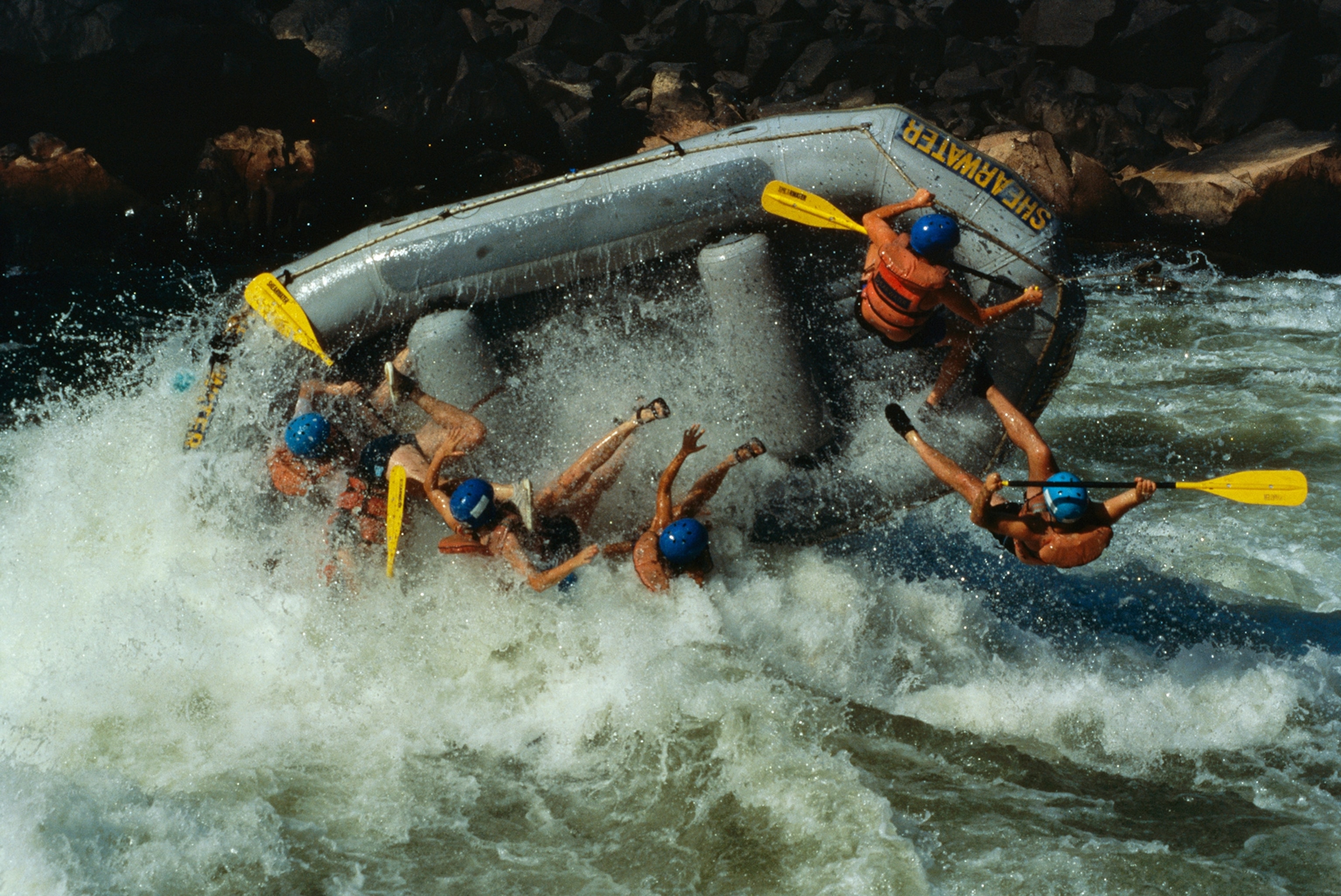 Class V rapids flip a raft full of whitewater enthusiasts.