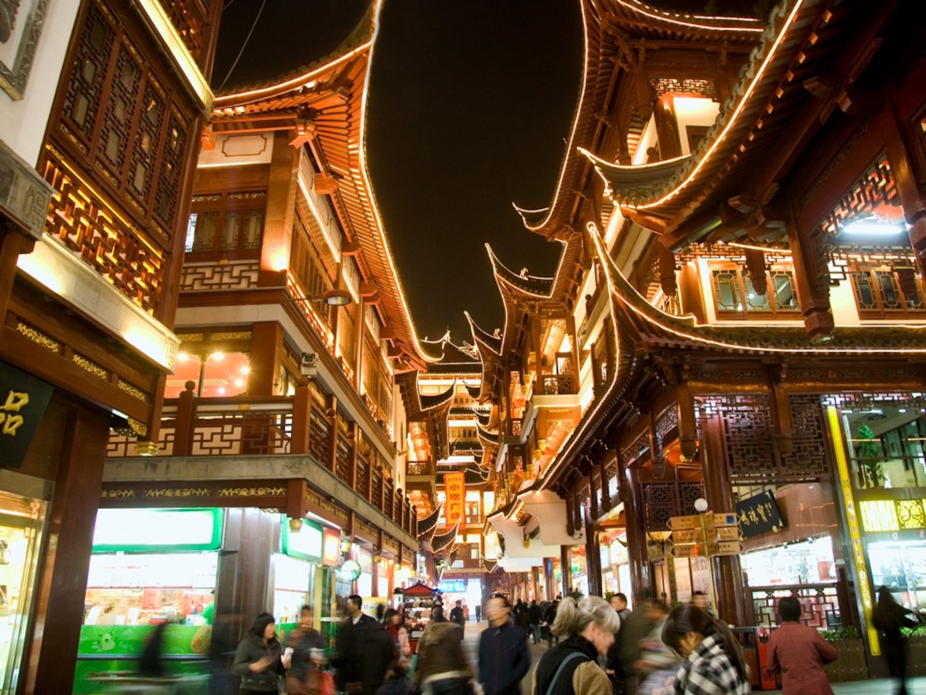 Tourists walk through brightly lit teahouses