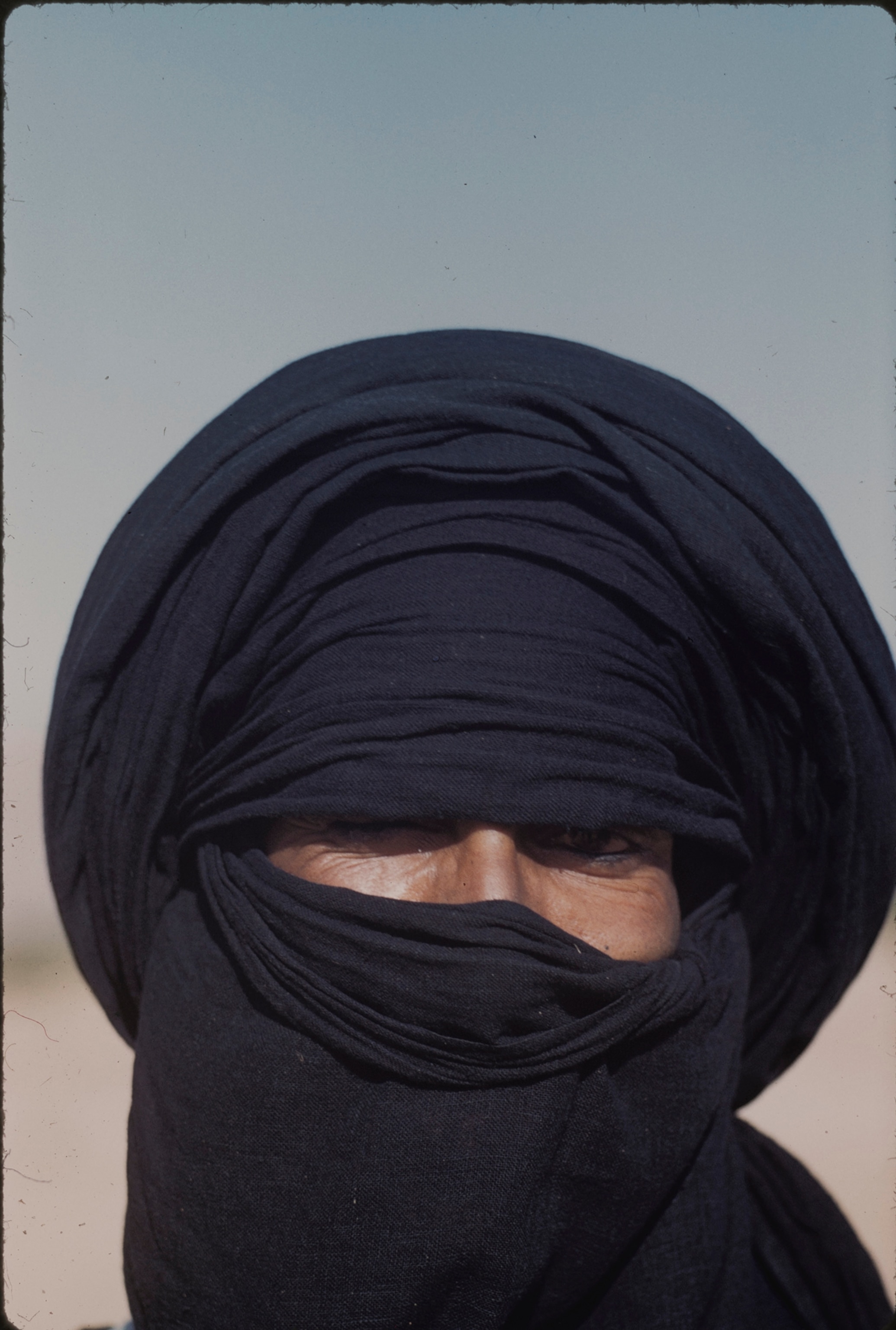 Veiled Tuareg tribesman, symbol of mystery in the Sahara, shrouds all but his eyes from the world.