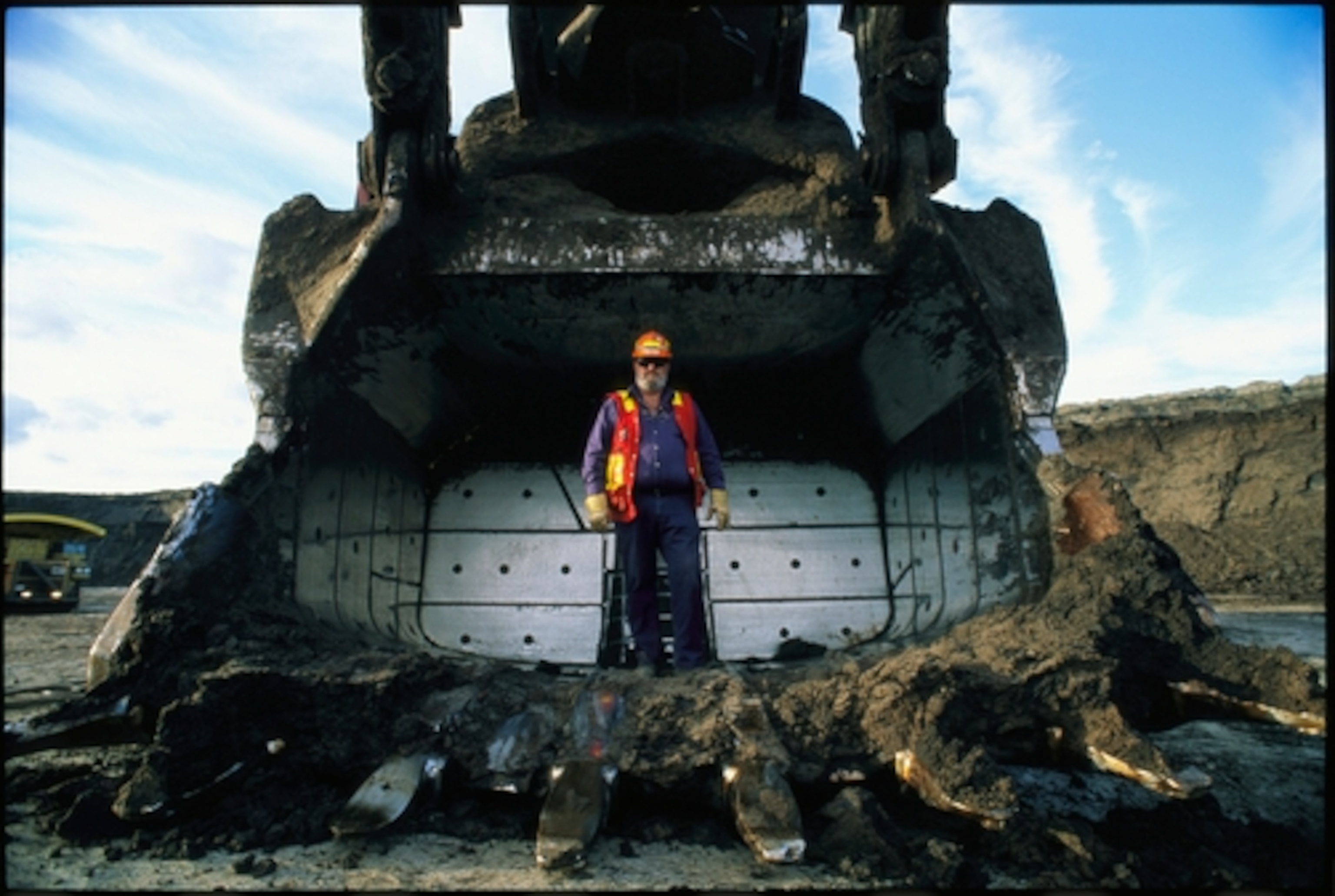 A worker stands in a giant scoop at a tar sands processing facility. Photograph by Sarah Leen, National Geographic