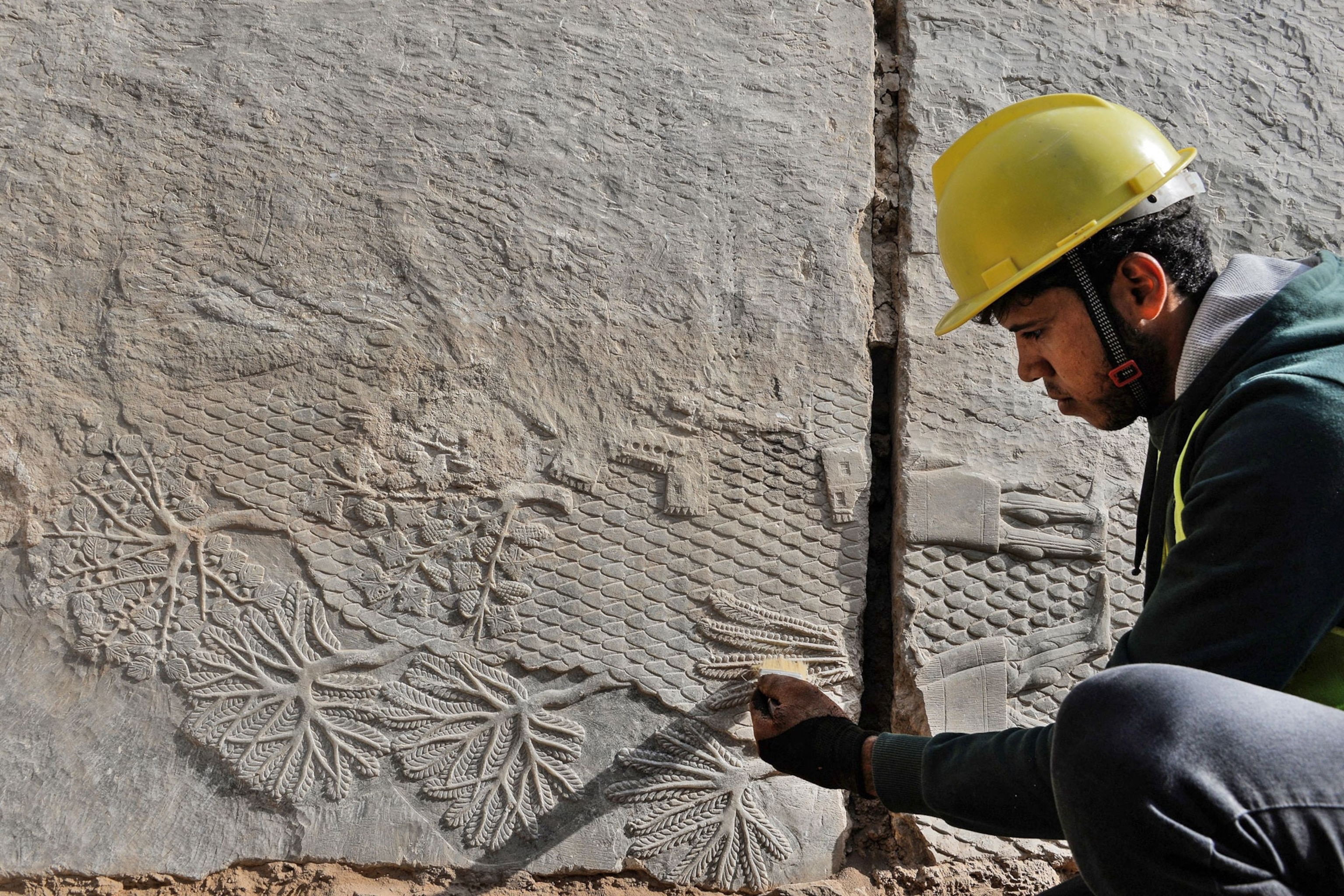 An Iraqi worker excavates a rock-carving relief recently found at the Mashki Gate