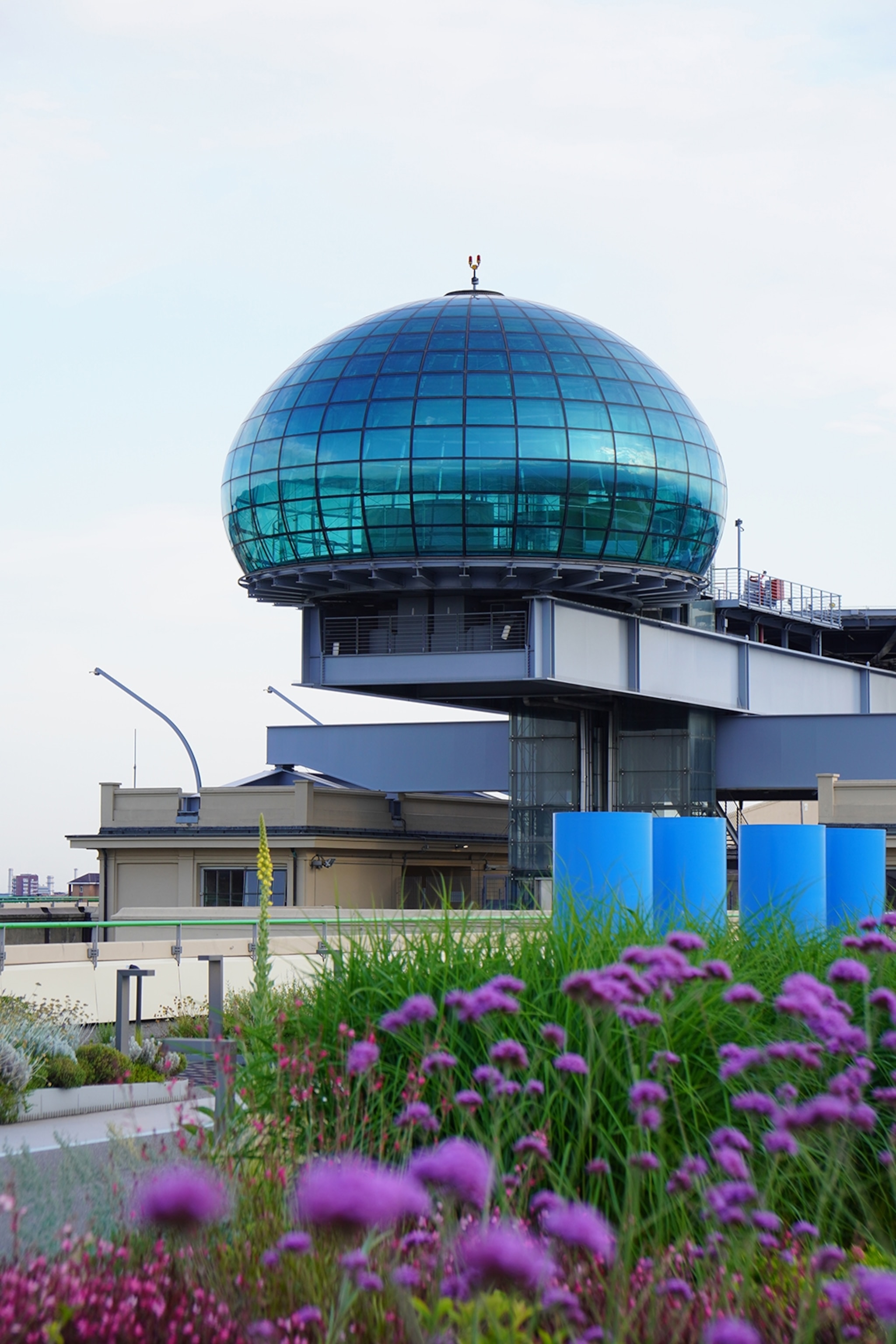 Image of a blue glass dome perched on the edge of a grey, contemporary building