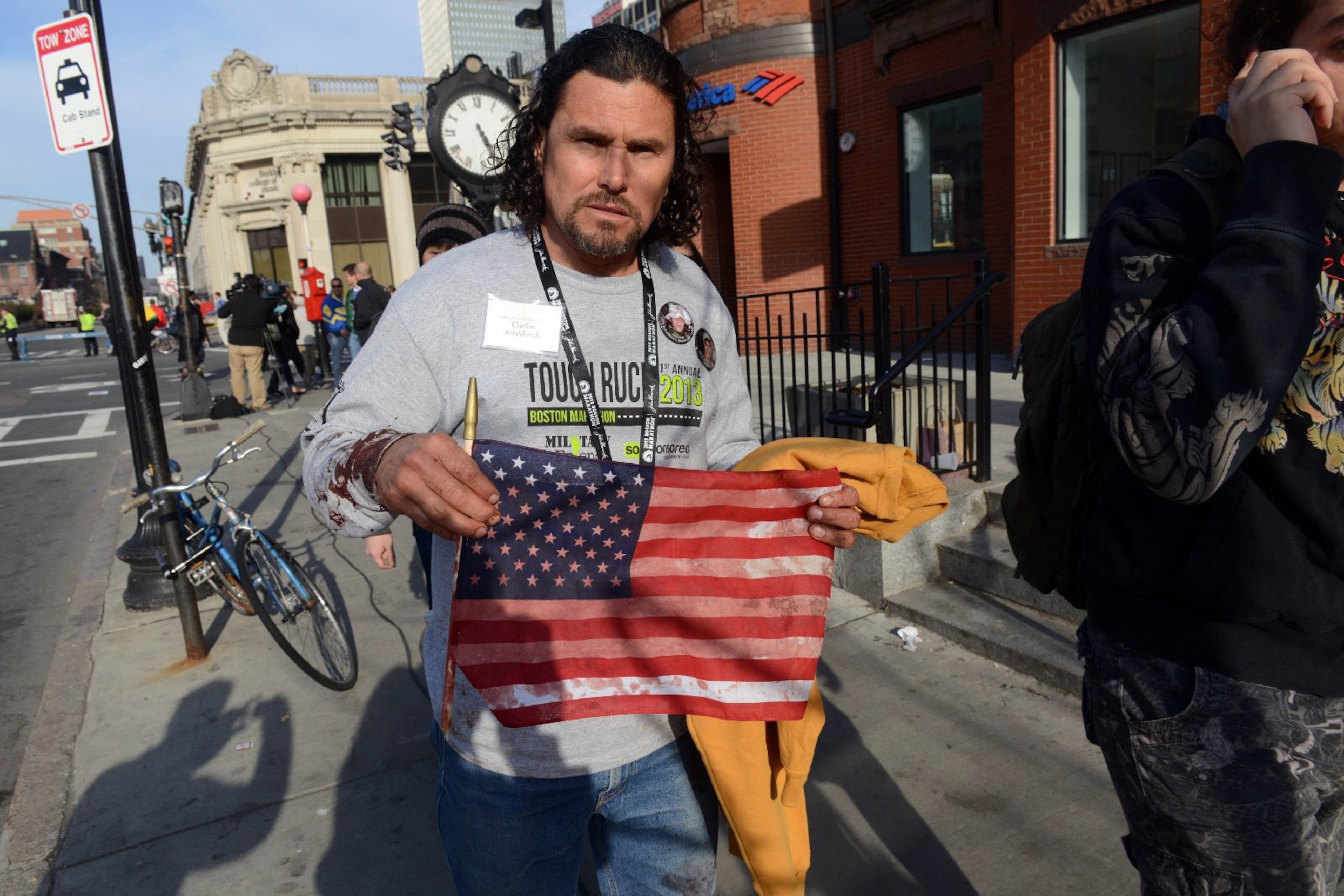 This Week in Boston - A man holds a bloodied American flag on a street in Boston.