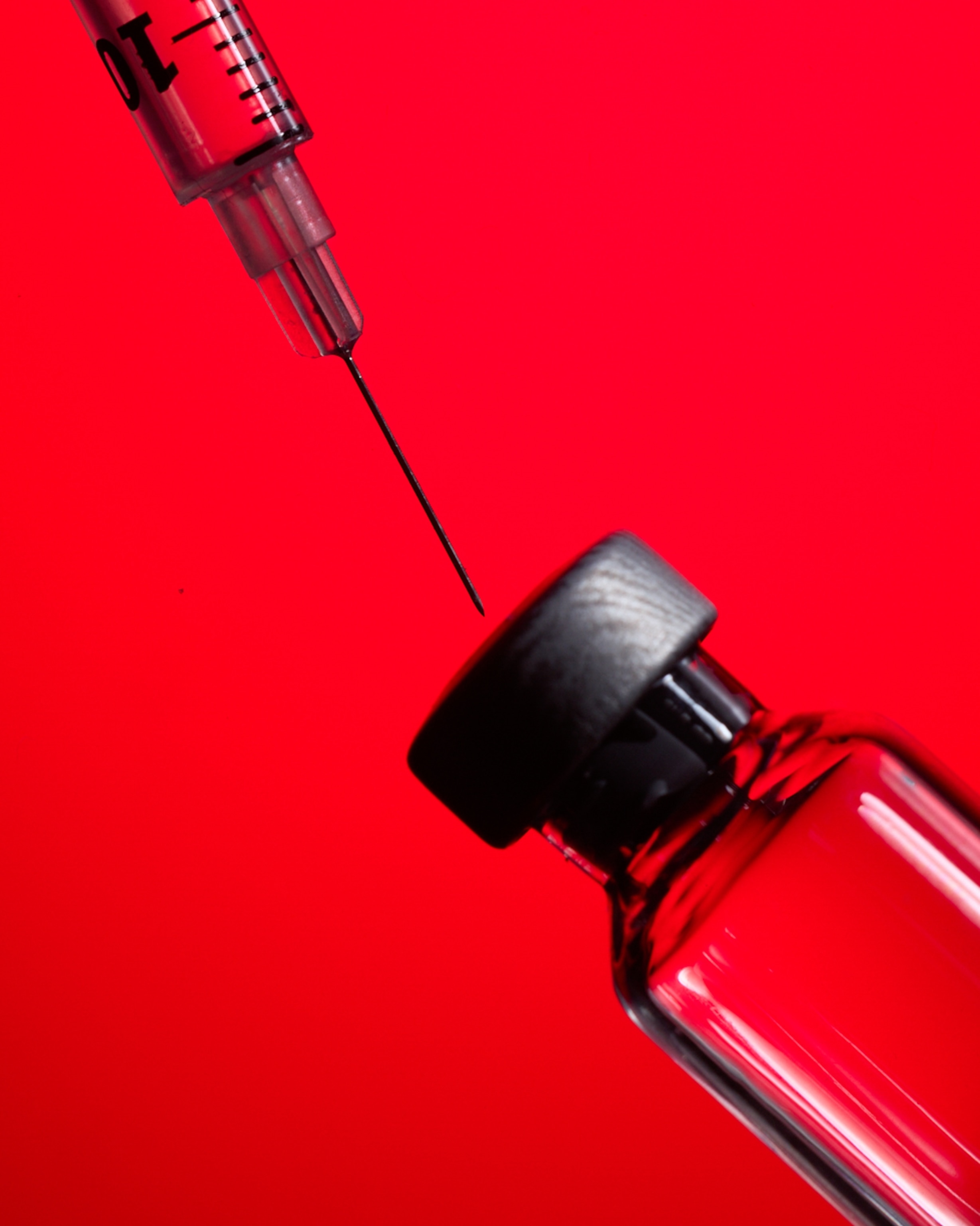 Needle about to extract liquid from a clear vial.