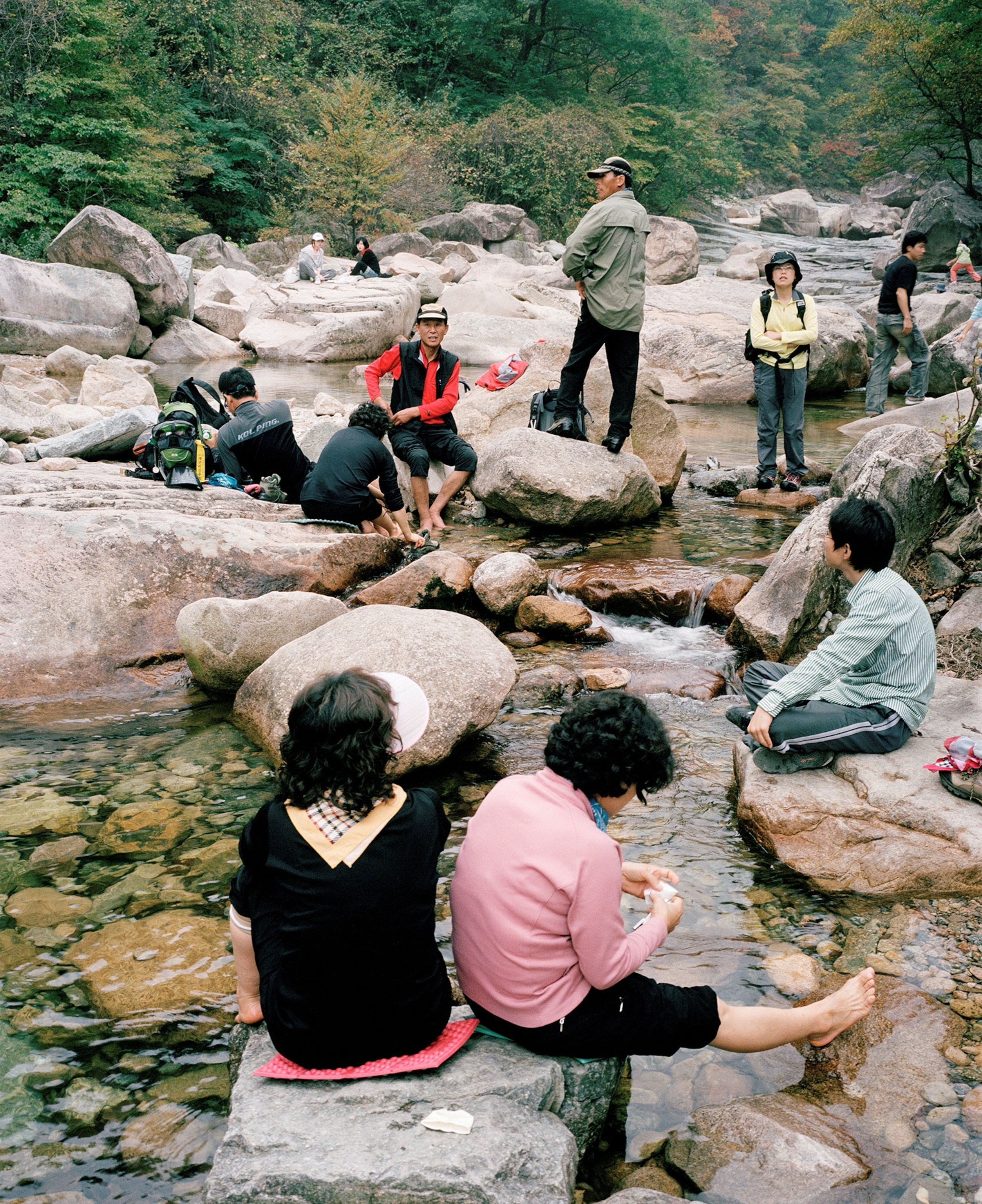 South Korea, Seoraksan National Park, hikers cooling feet in stream.