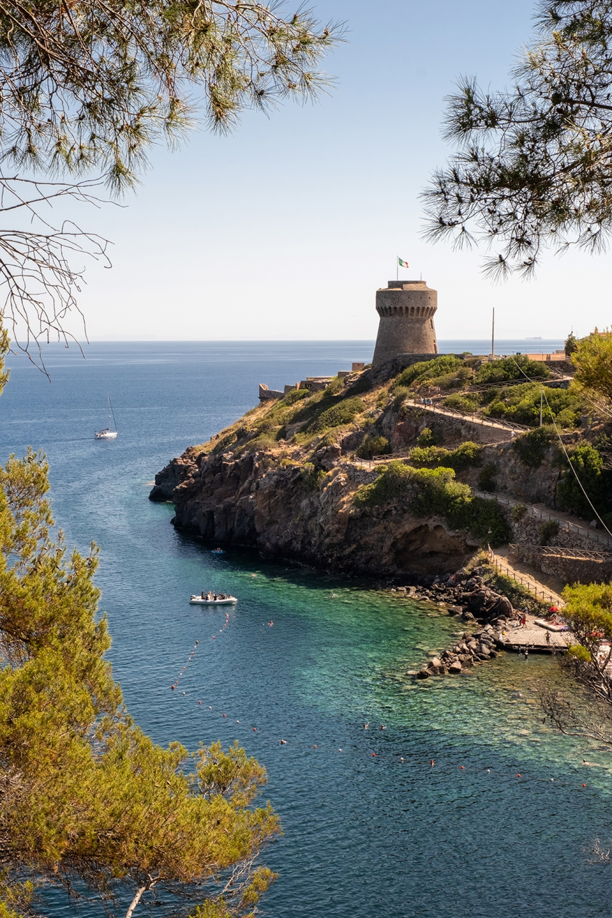 The rugged coast of an Italian island with an old stone tower overlooking the ocean.