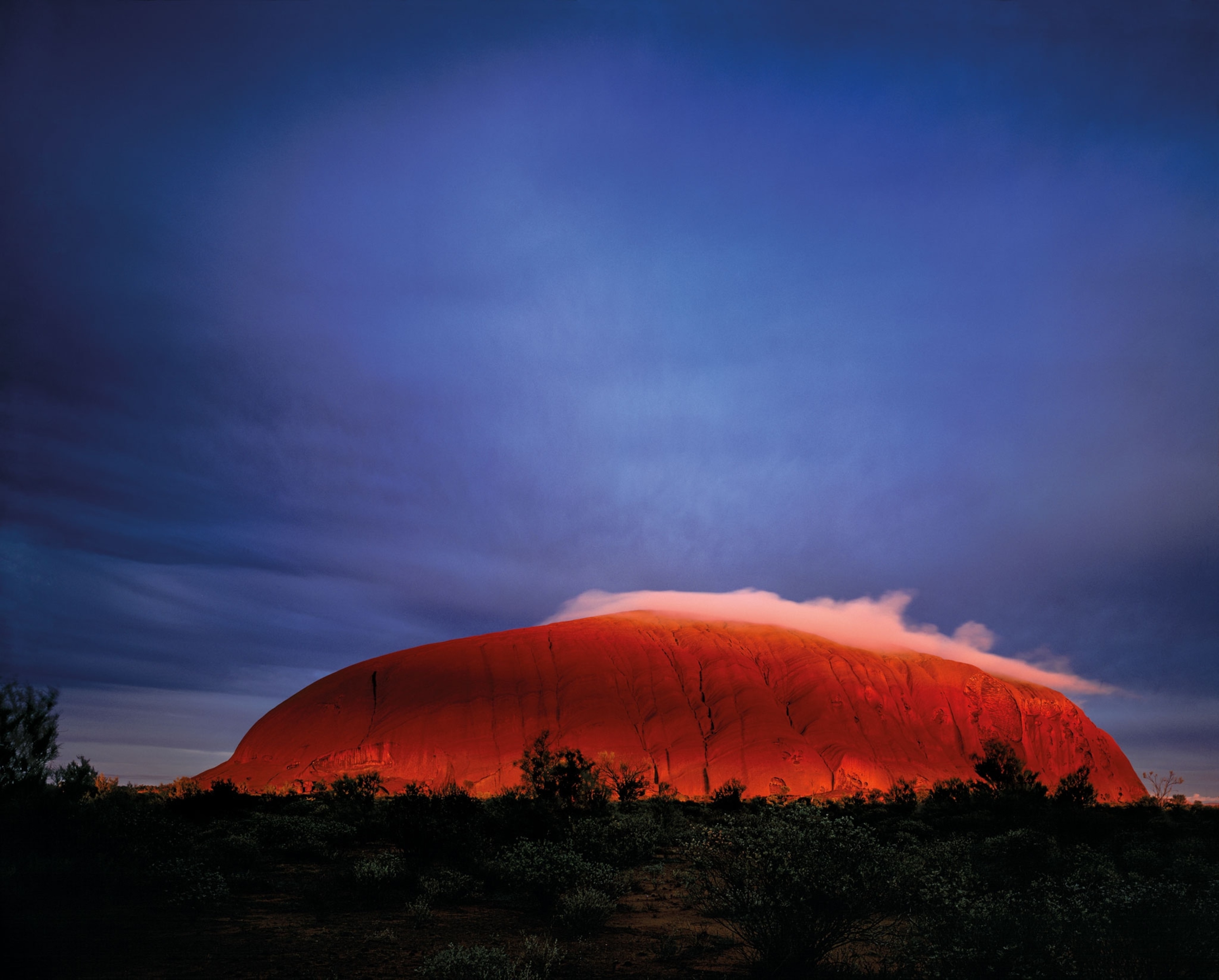 Red in the light, a sandstone outcropping is tall on the landscape.