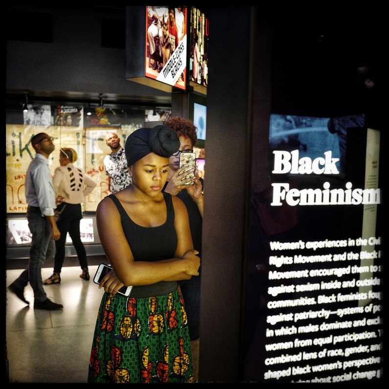 A young lady takes a moment to read about the struggles of black feminism.
