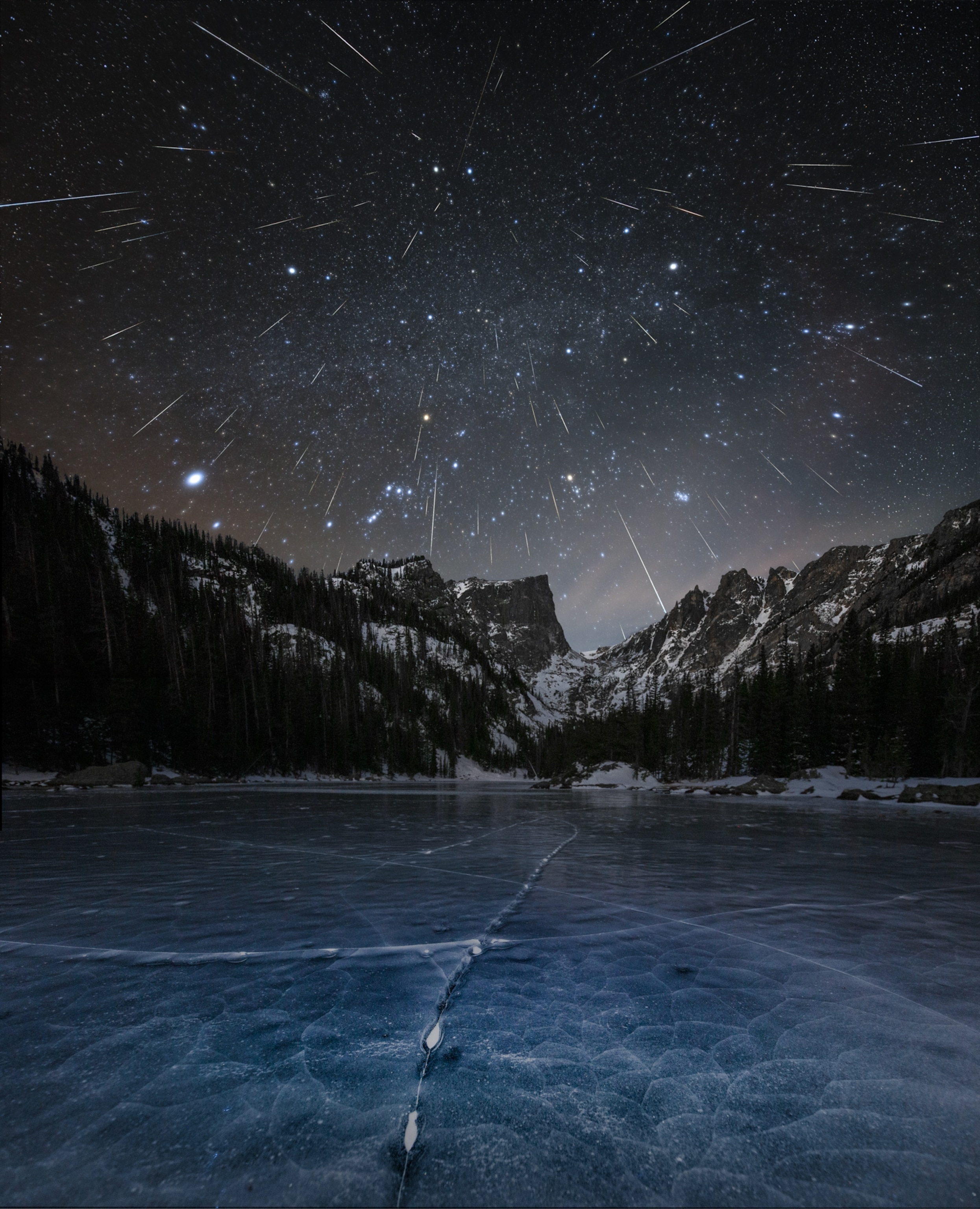 Dozens of bright streaks in the night sky above a frozen lake