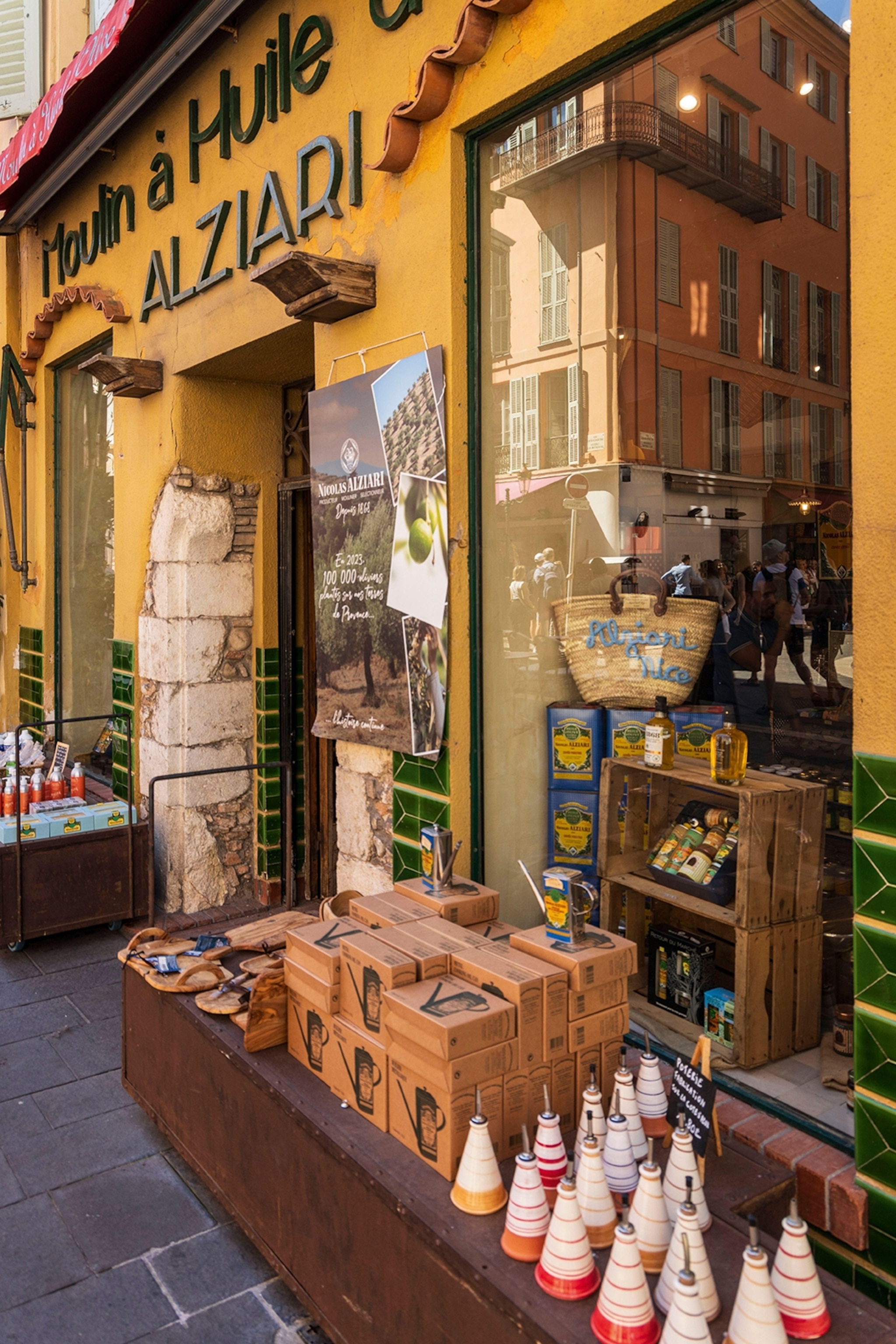 The shopfront of a small alleyway olive oil vendor, displaying boxes and ceramic bottles both inside and outside.