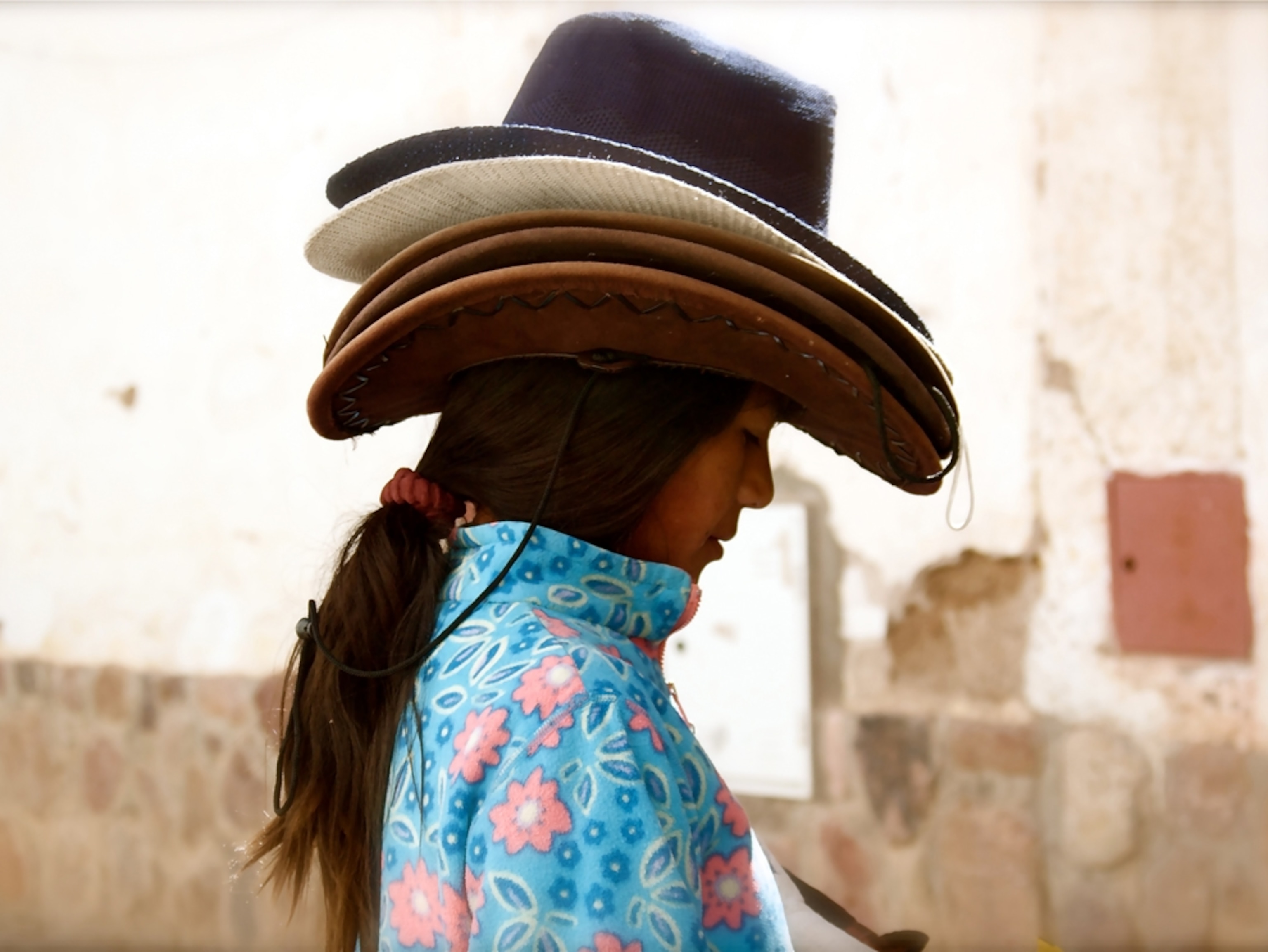 A young girl wearing several cowboy hats