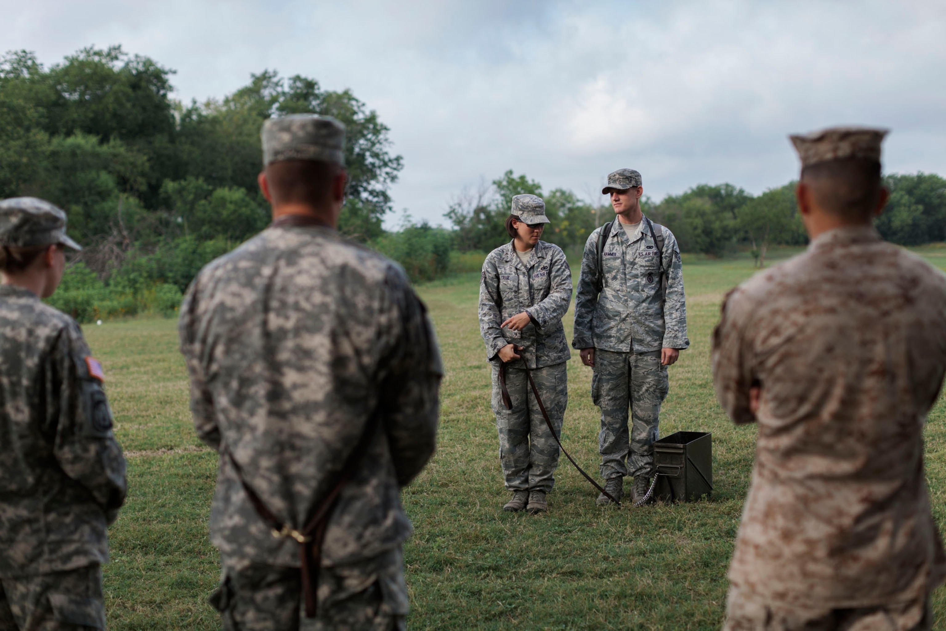 Picuture of handlers use an ammunition can as a dog stand-in to learn leash skills and hand signals.