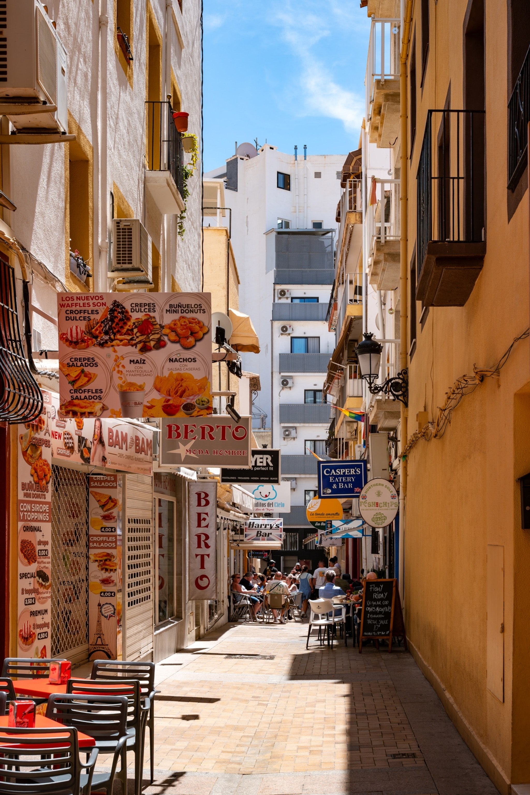 Benidorm, Spain, 3. May 2024– Narrow street with restaurants, cafés, and shops on a sunny summer day in the city center.