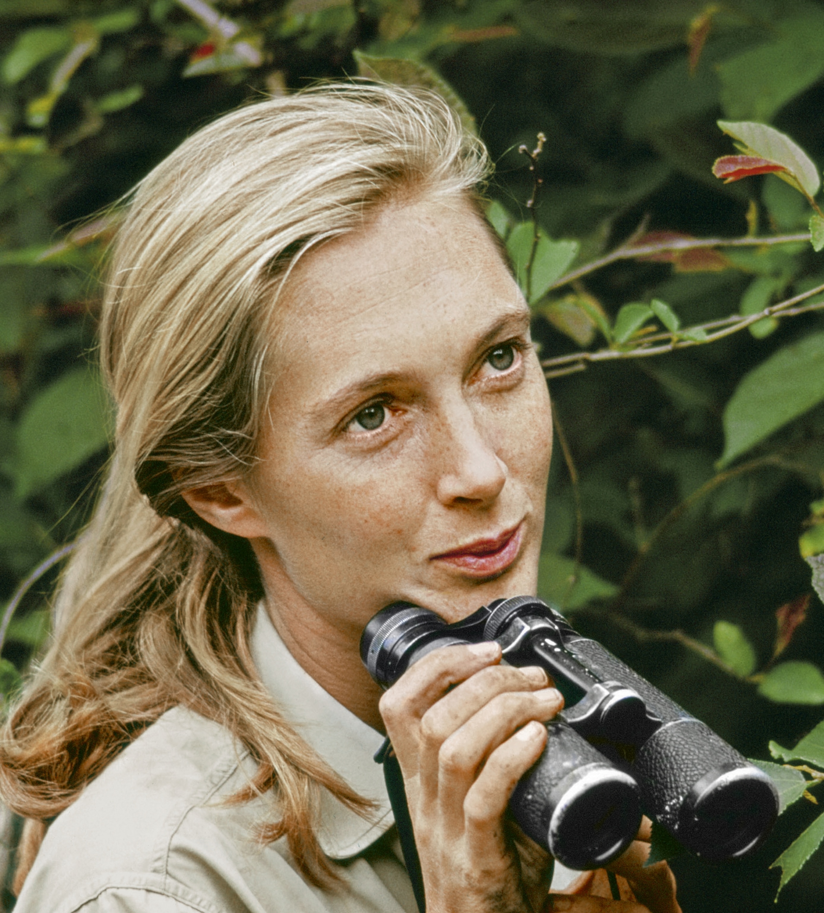 Young blond woman with binocular in right hand.