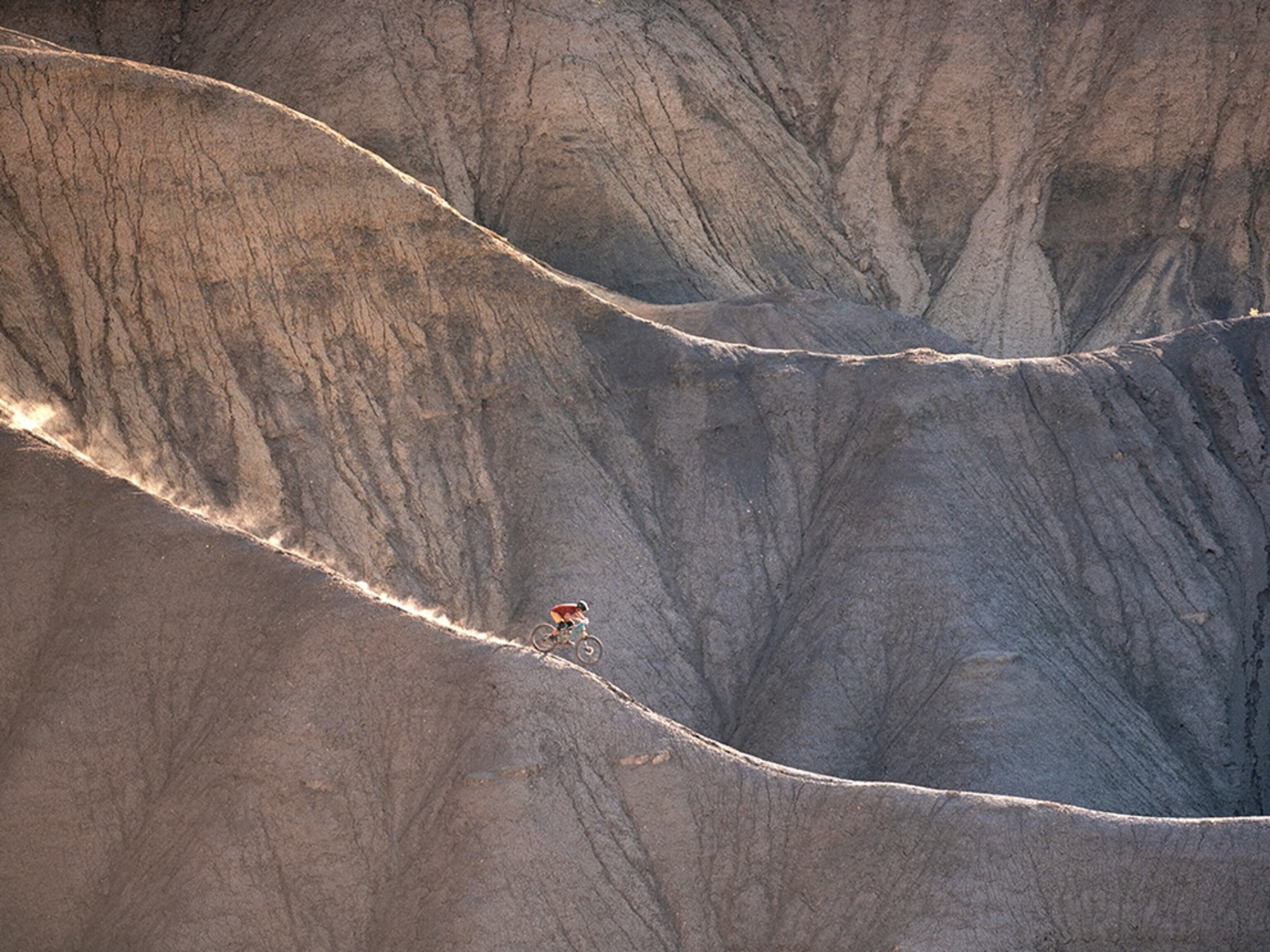 a man riding a mountain bike down a slender ridge in Utah.