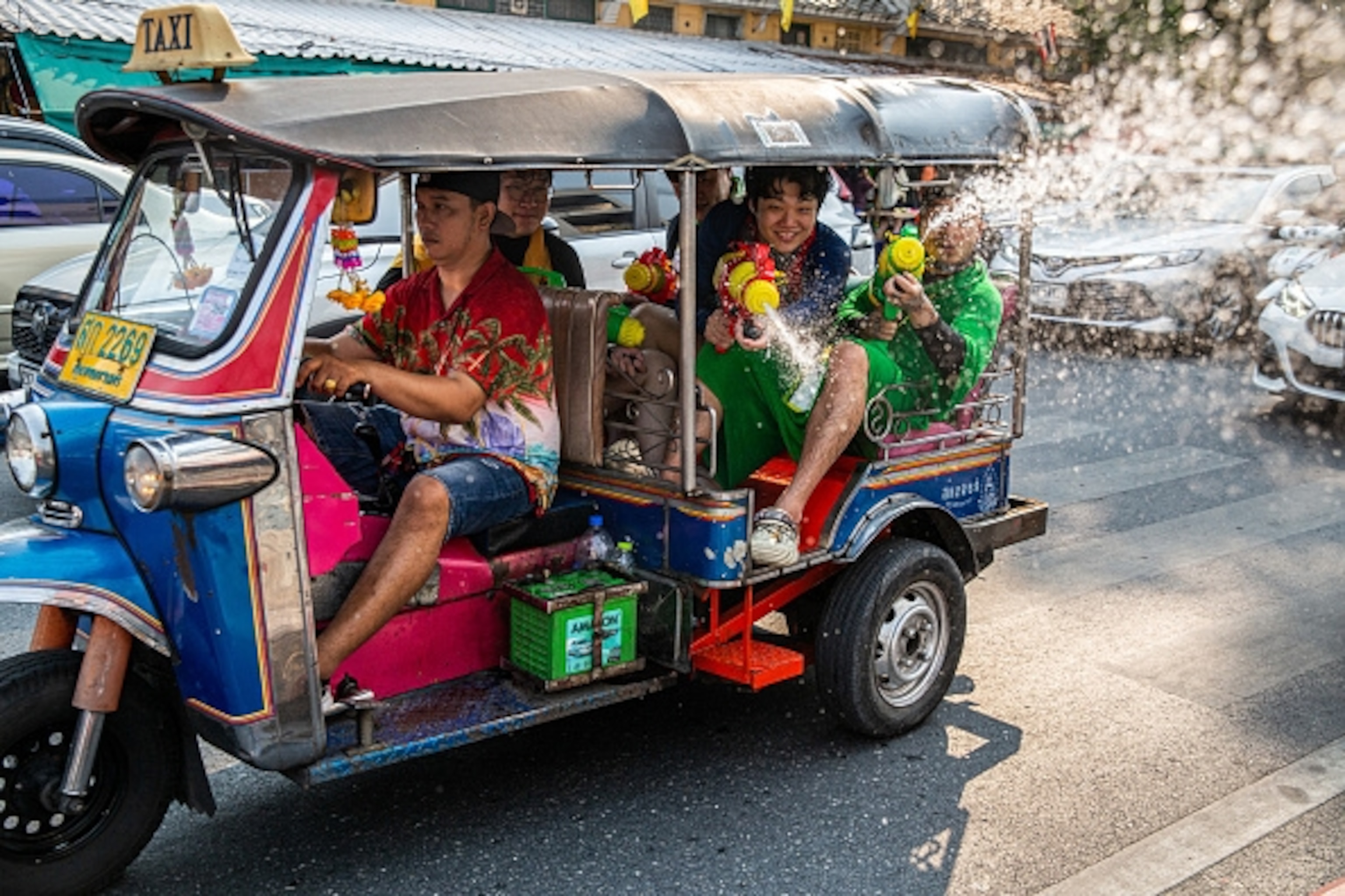 A man drives people in a kart as they spray water guns.