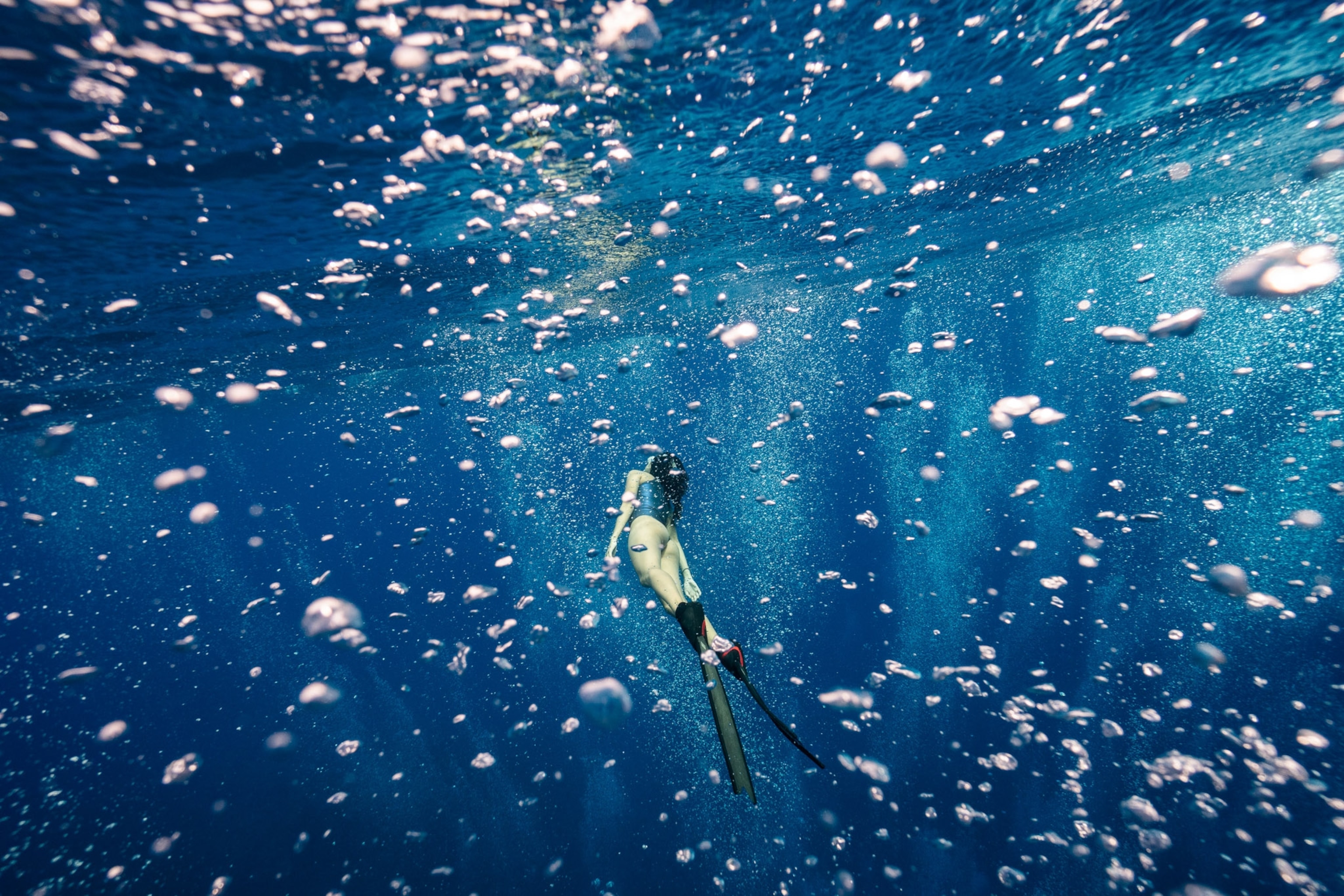 Bubbles rise up filling the frame you see a diver swimming through them.