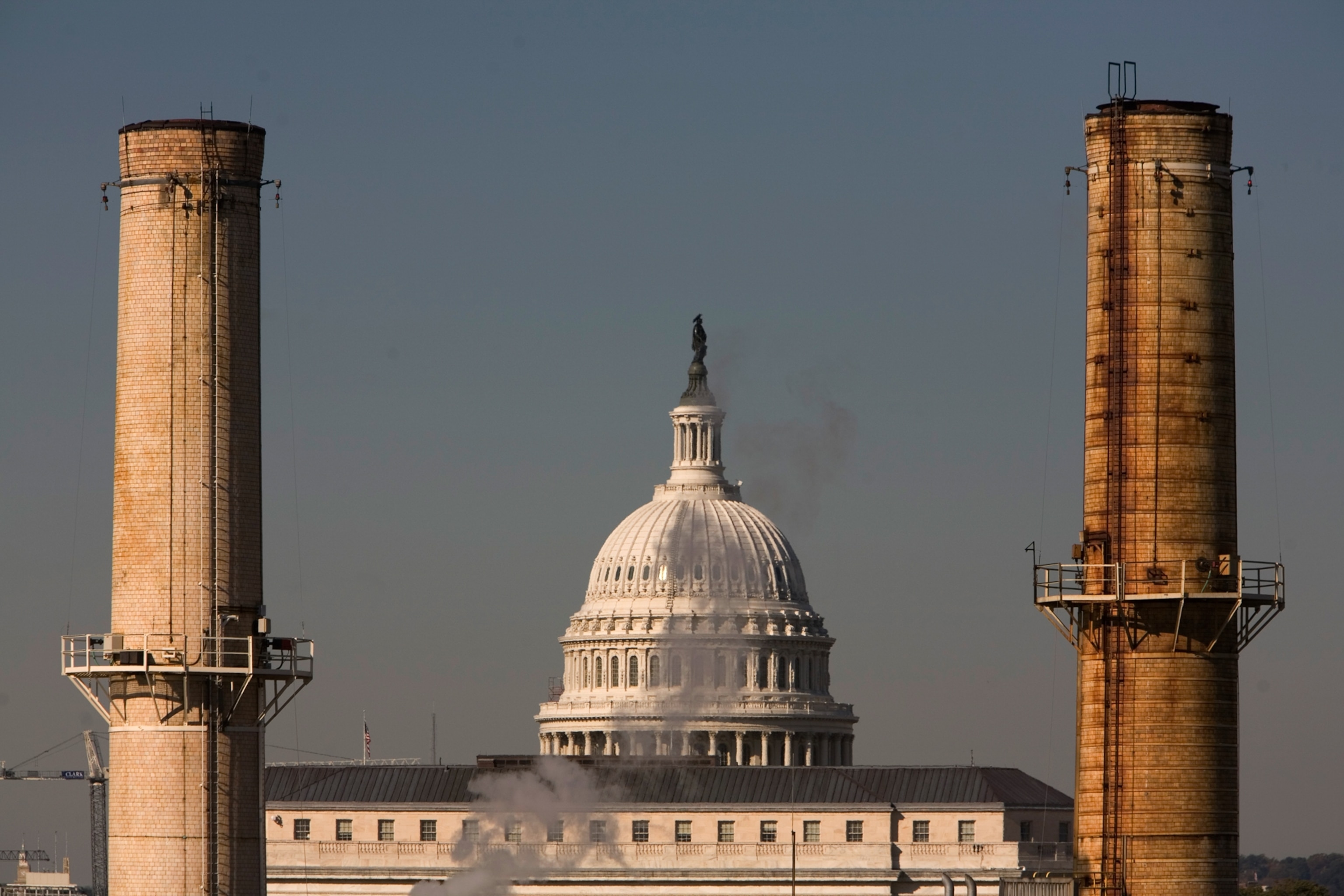 The Capitol dome looms behind smokestacks of a coal-fired power plant.