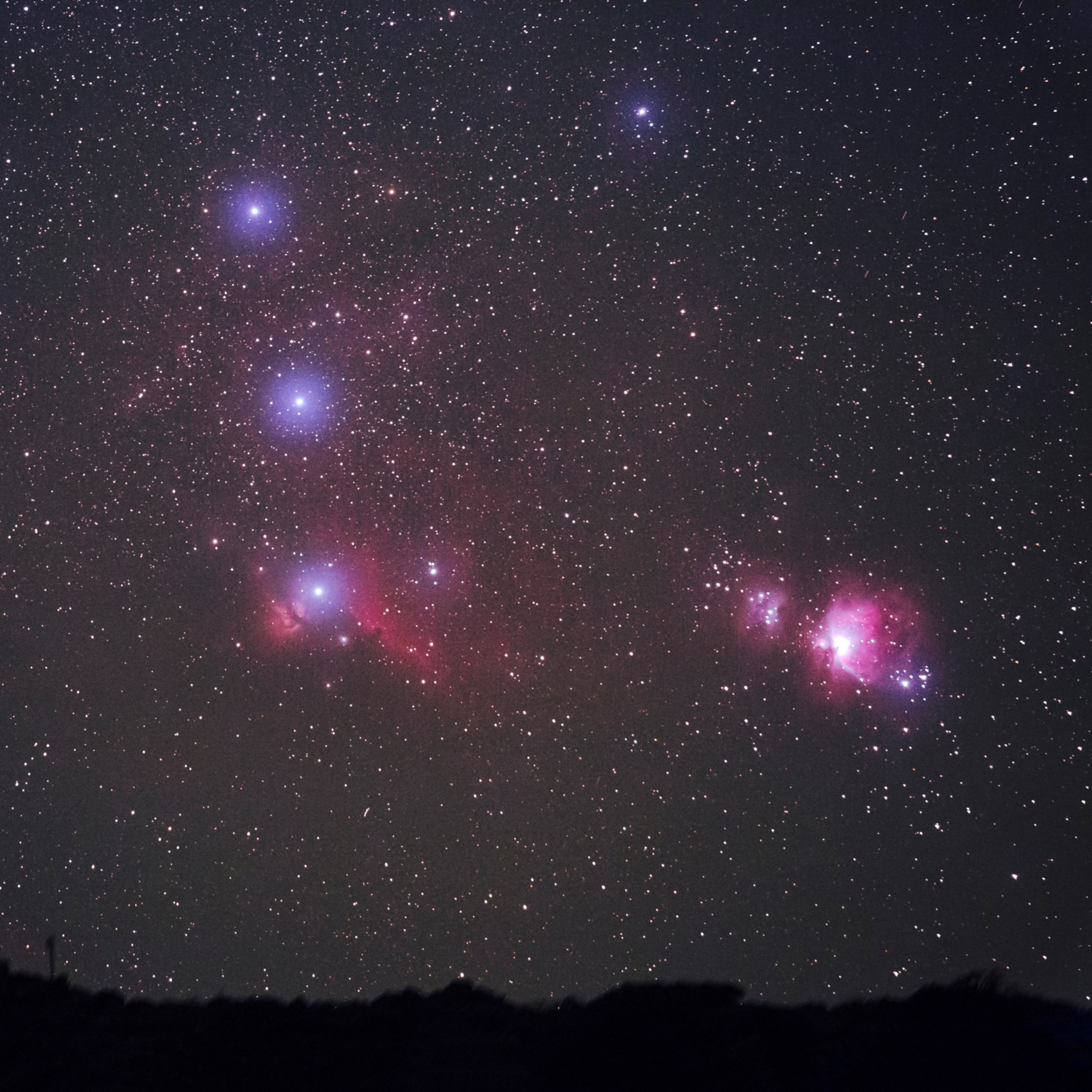 The pink and purple haze of Orion Nebula glowing amongst the bright stars of Orion's Belt