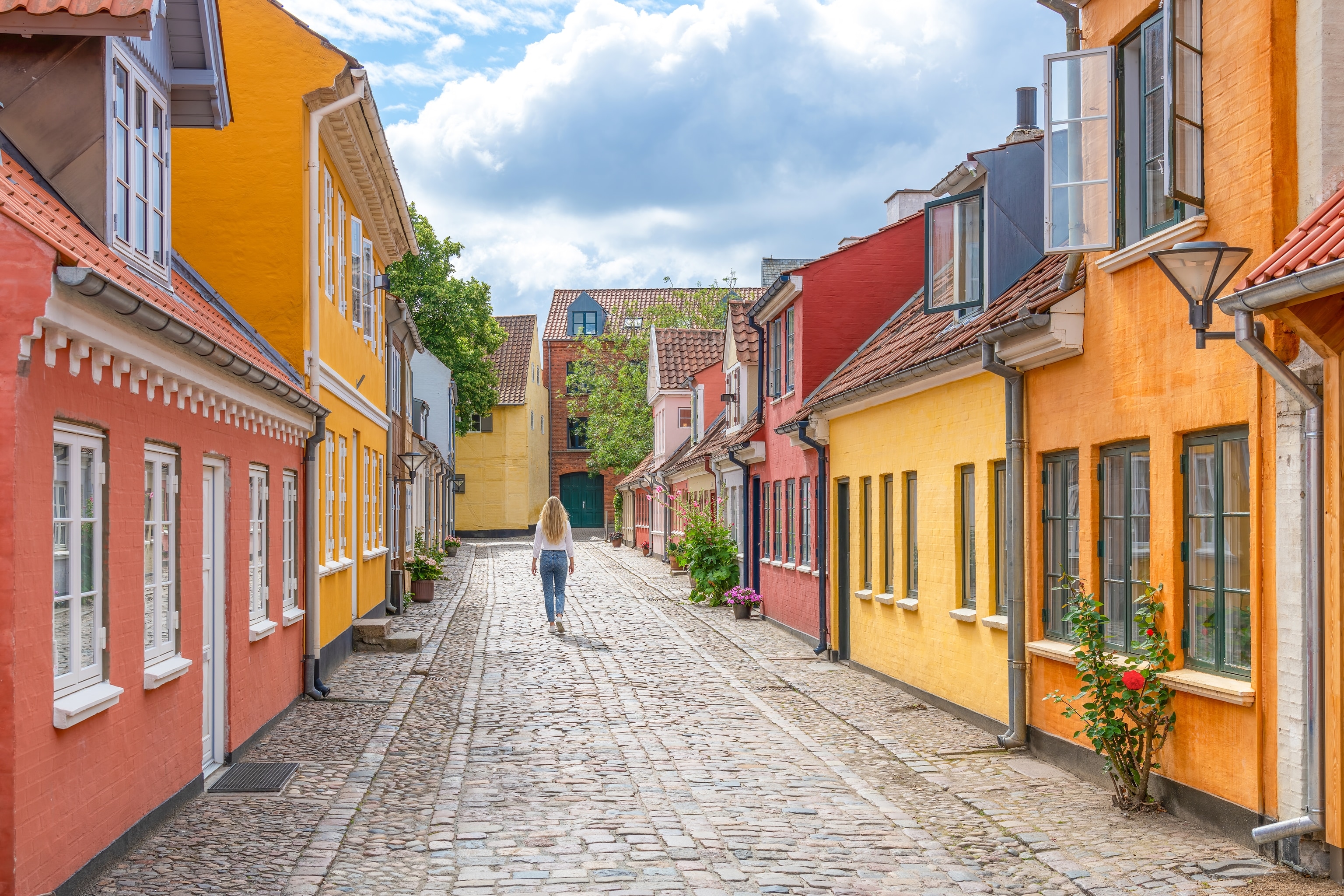 A cobbled street in Odense, Denmark with red, orange and yellow coloured houses.