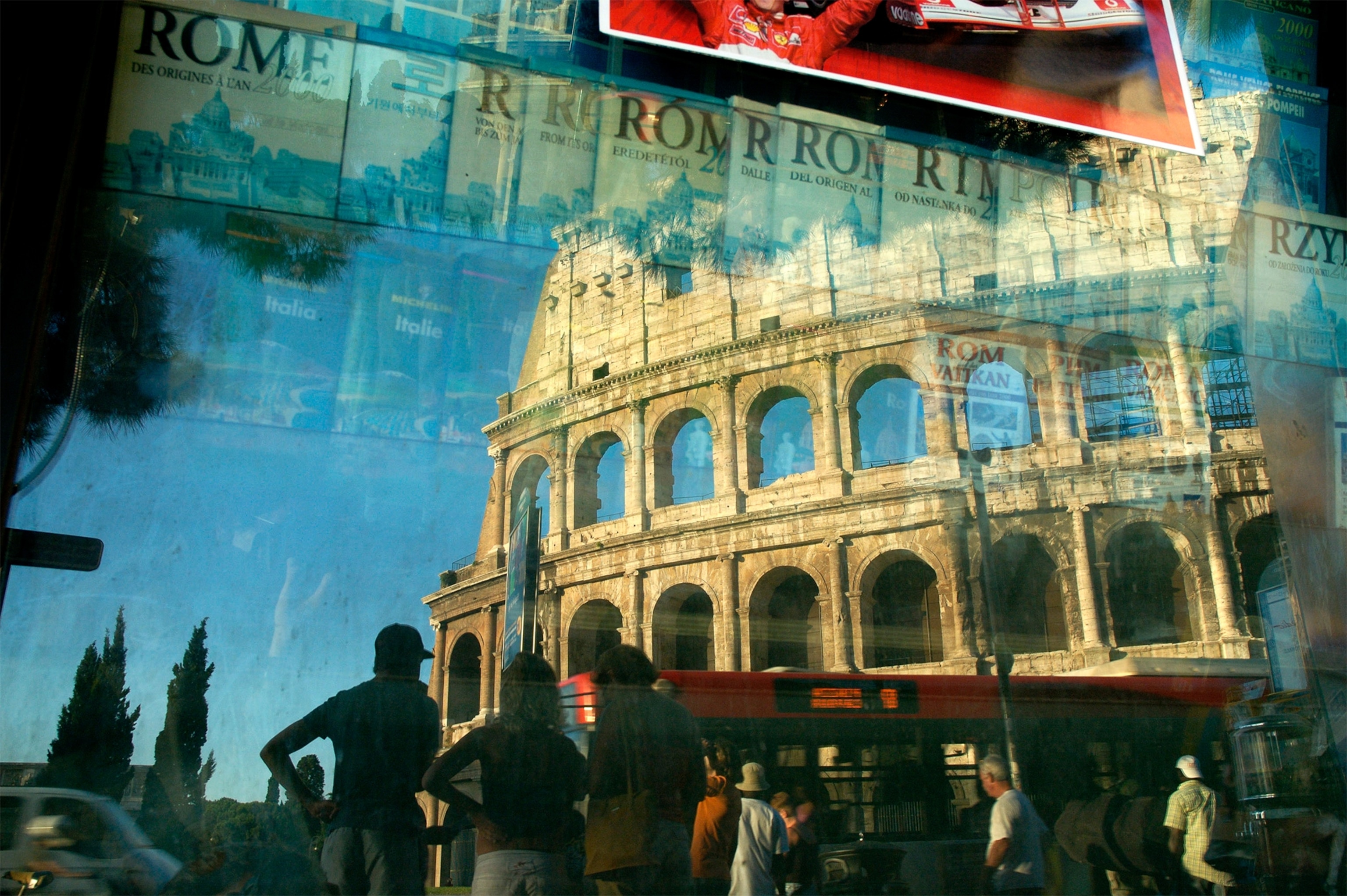 the reflection of the Colosseum and people waiting at a bus stop in Rome, Italy