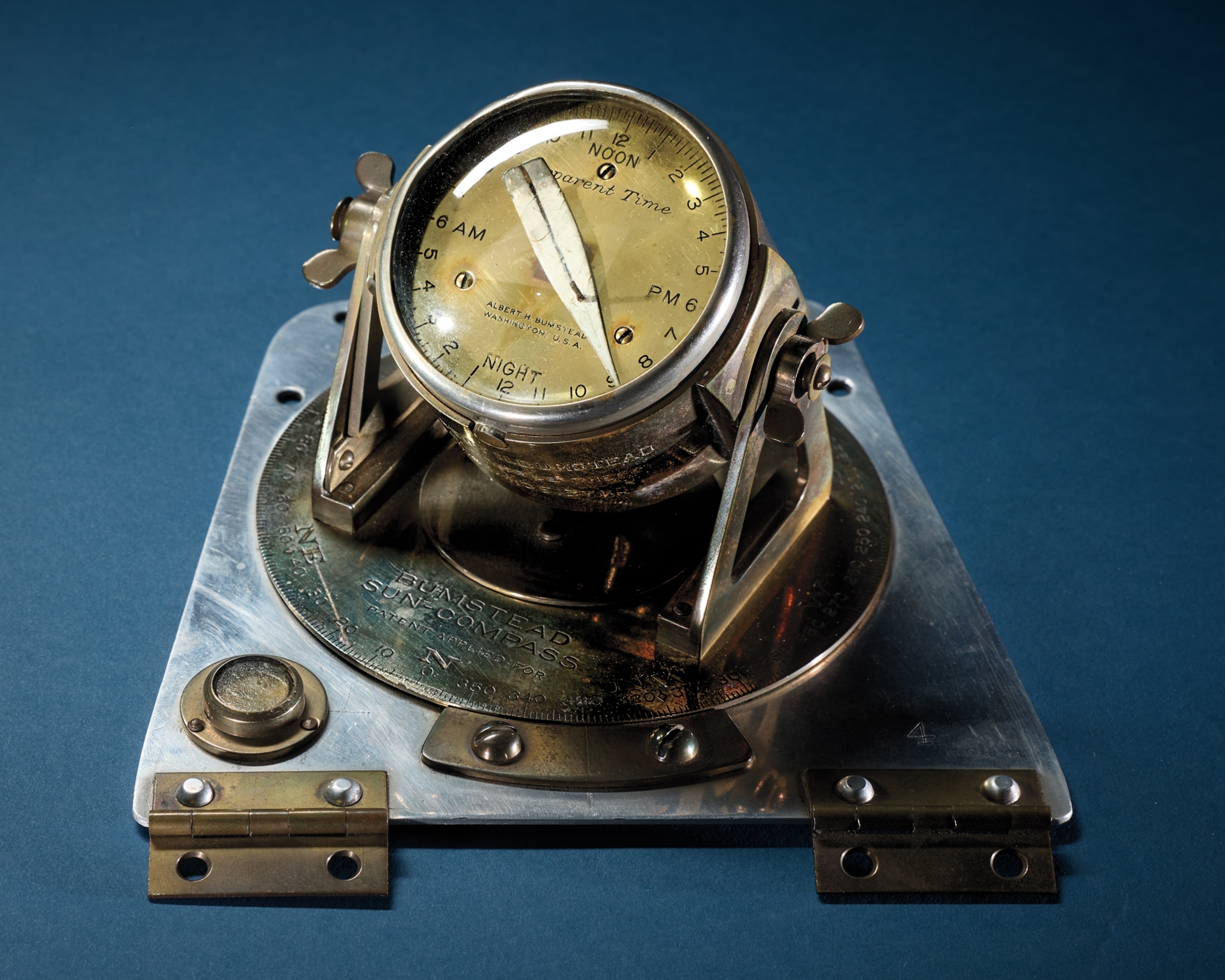 Brass instrument on still plate with brass hinges.