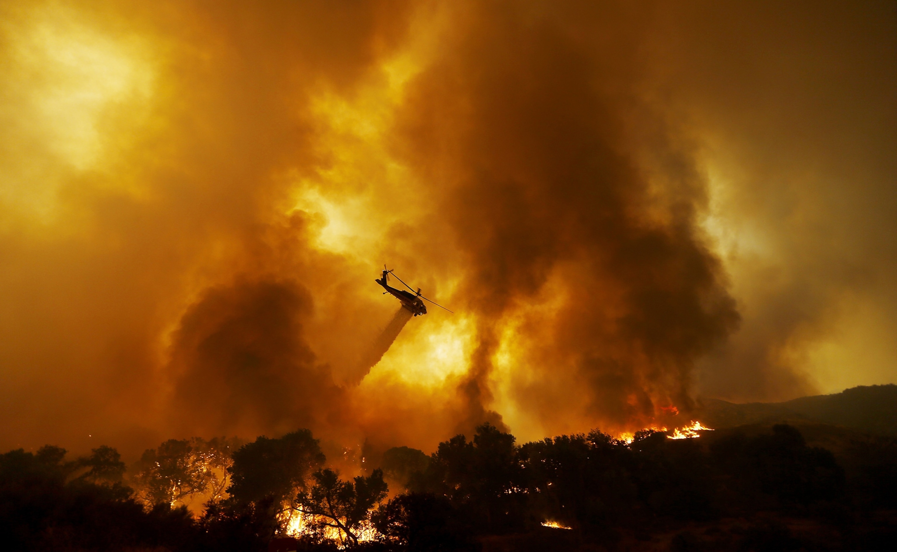 a firefighting helicopter dropping water on the Sand Fire