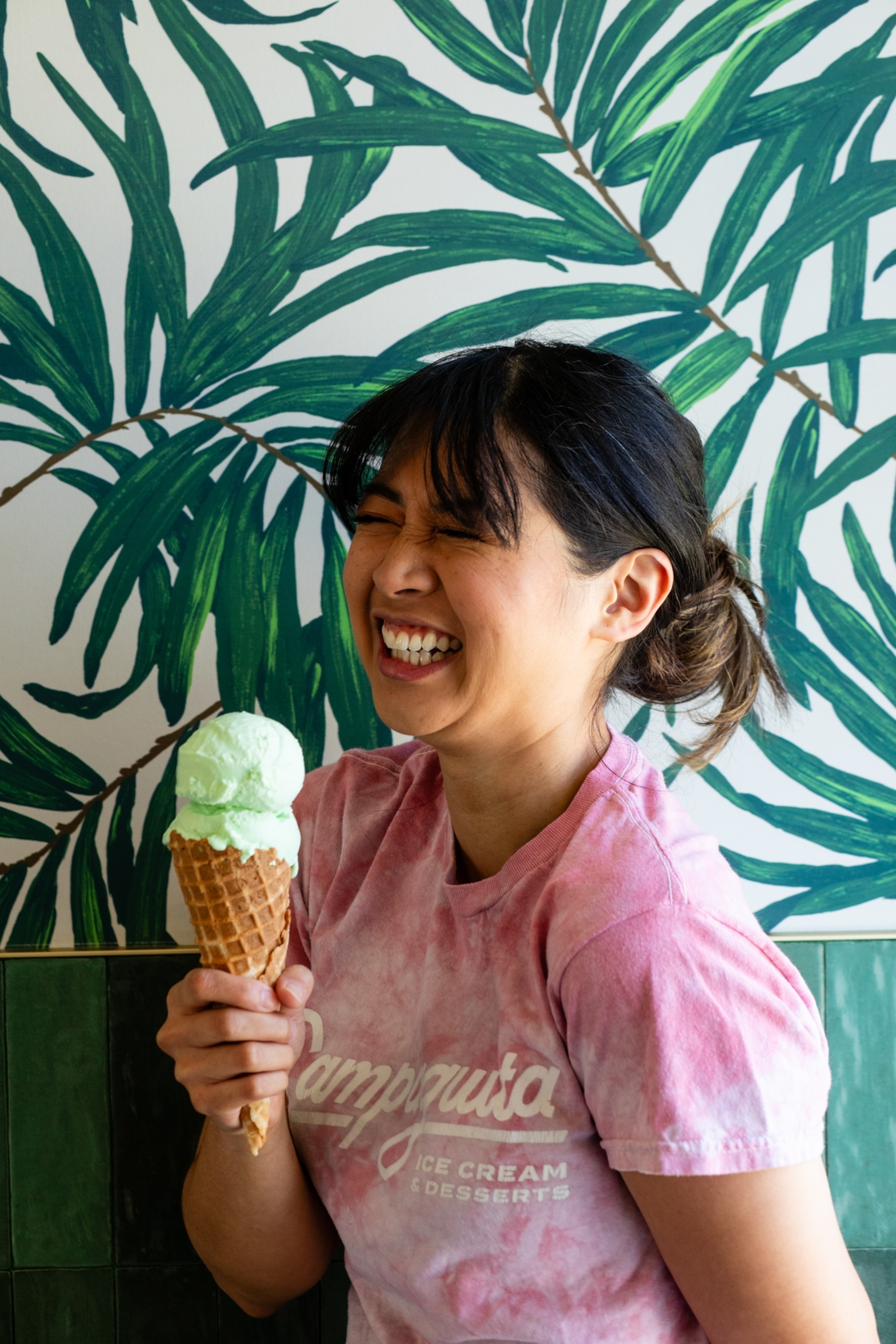 A woman smiling while holding an ice cream cone