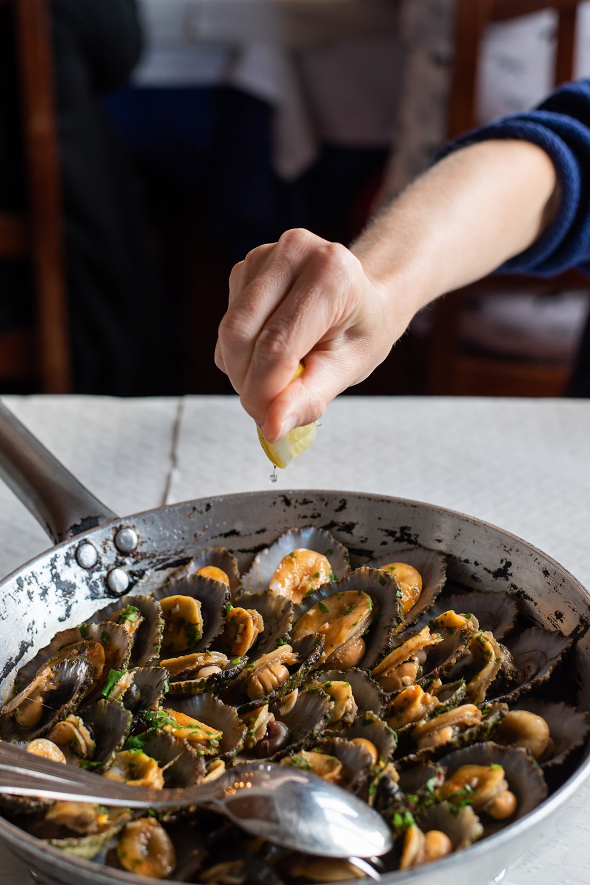 A skillet of fried limpets in the shells with herbs and lemon.