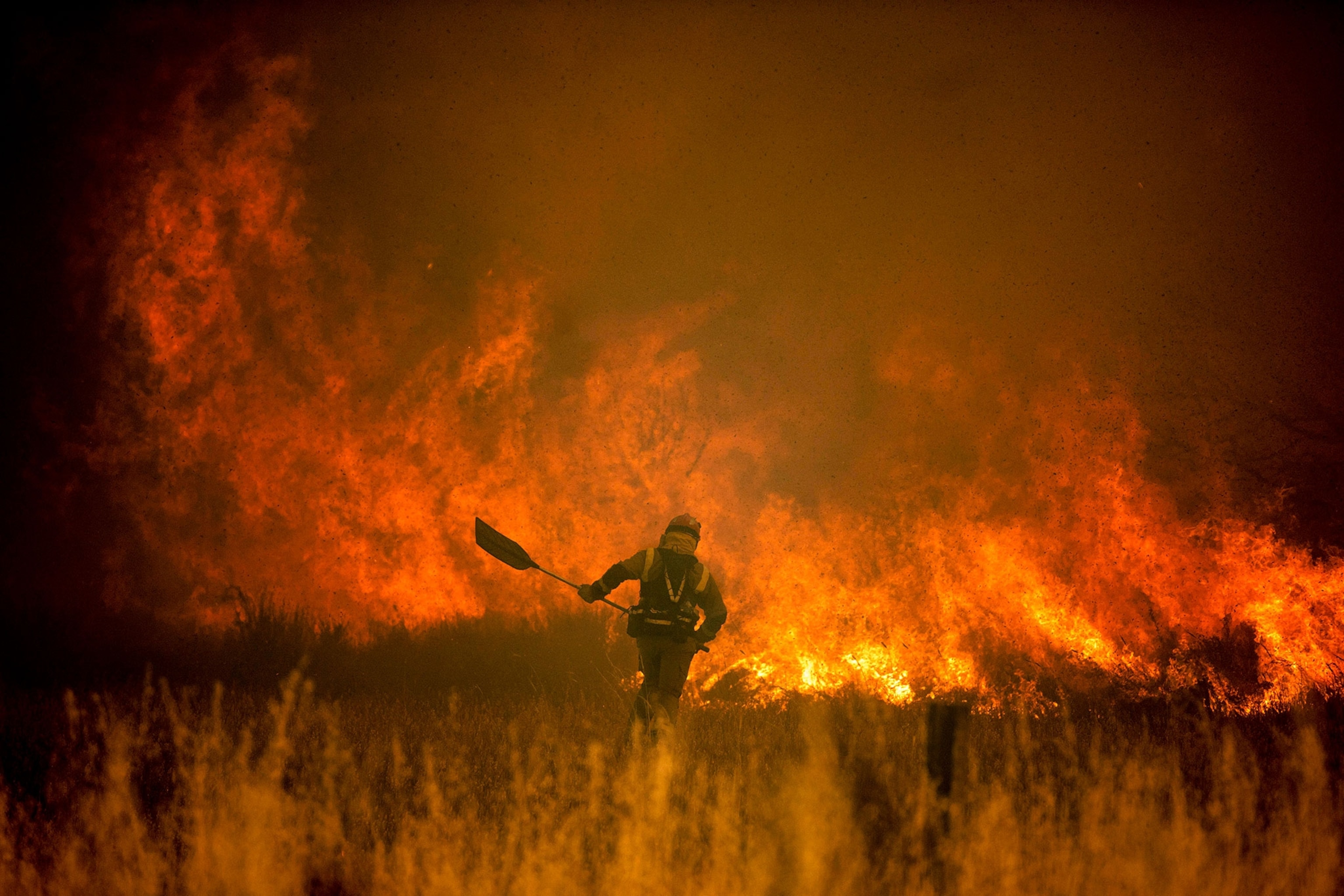 A man in front of flaming fire.