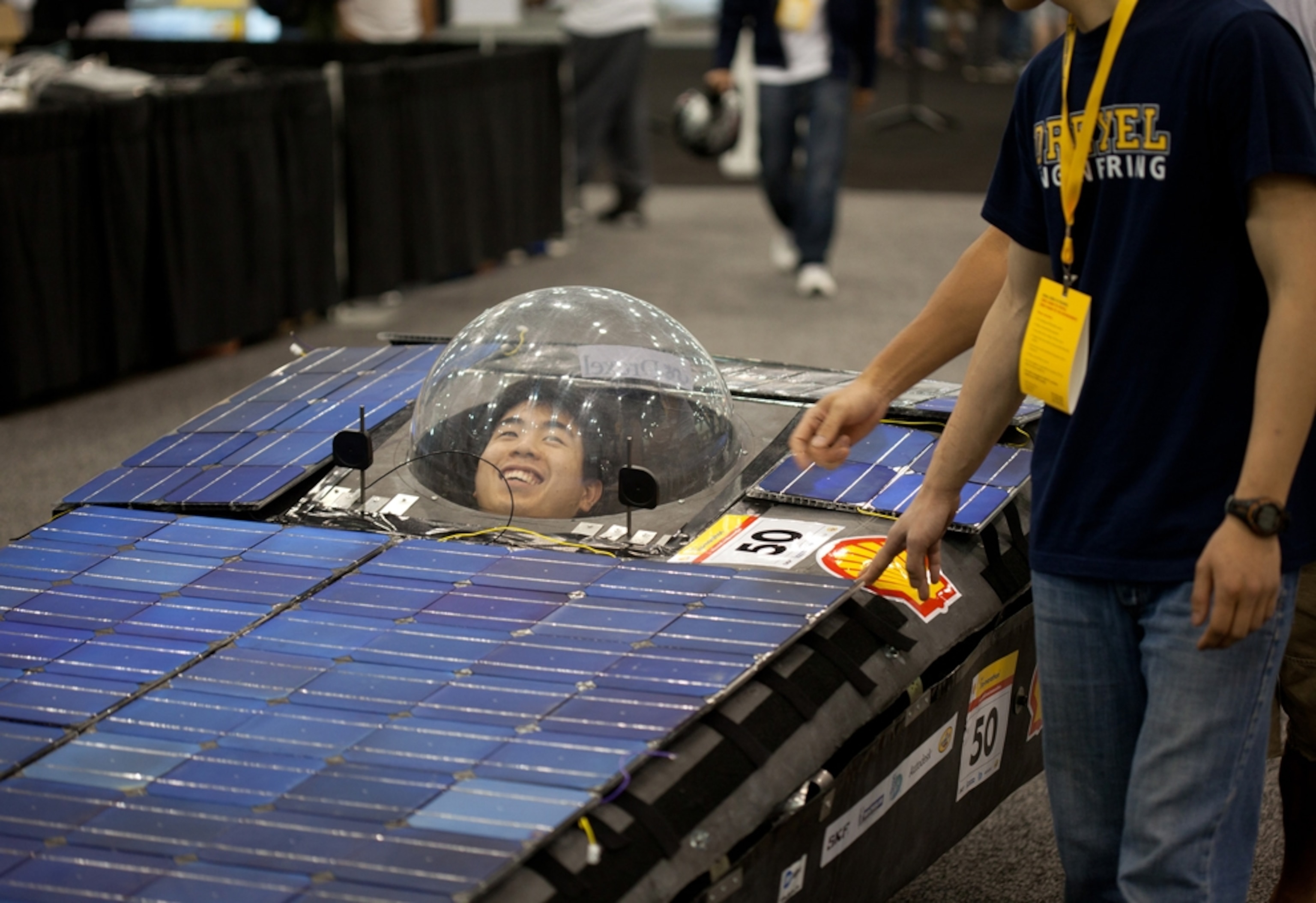 Driver peers from inside a plastic bubble atop a wide blue vehicle