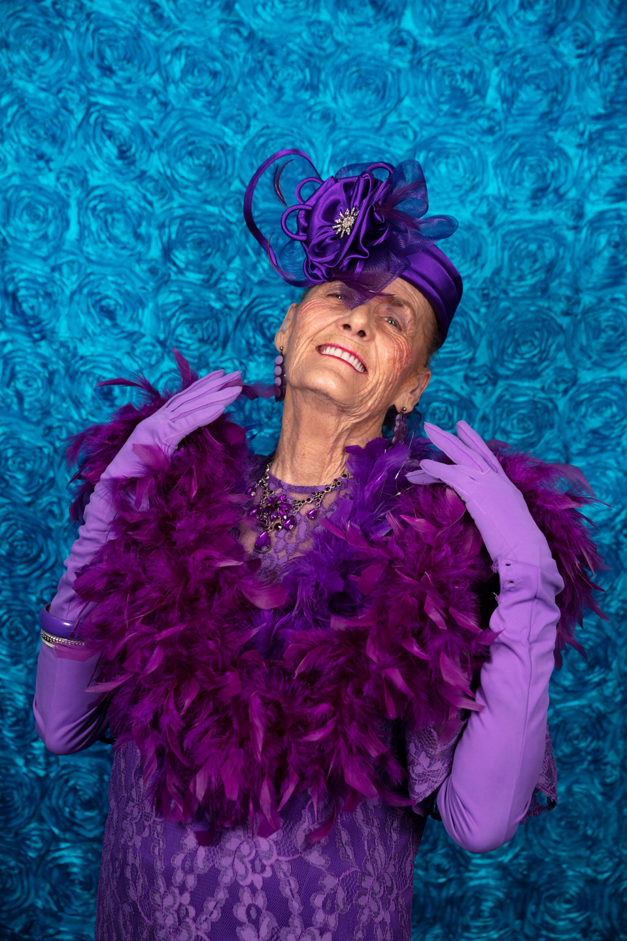 Picture of woman dressed in all purple, including the purple hat and boa.