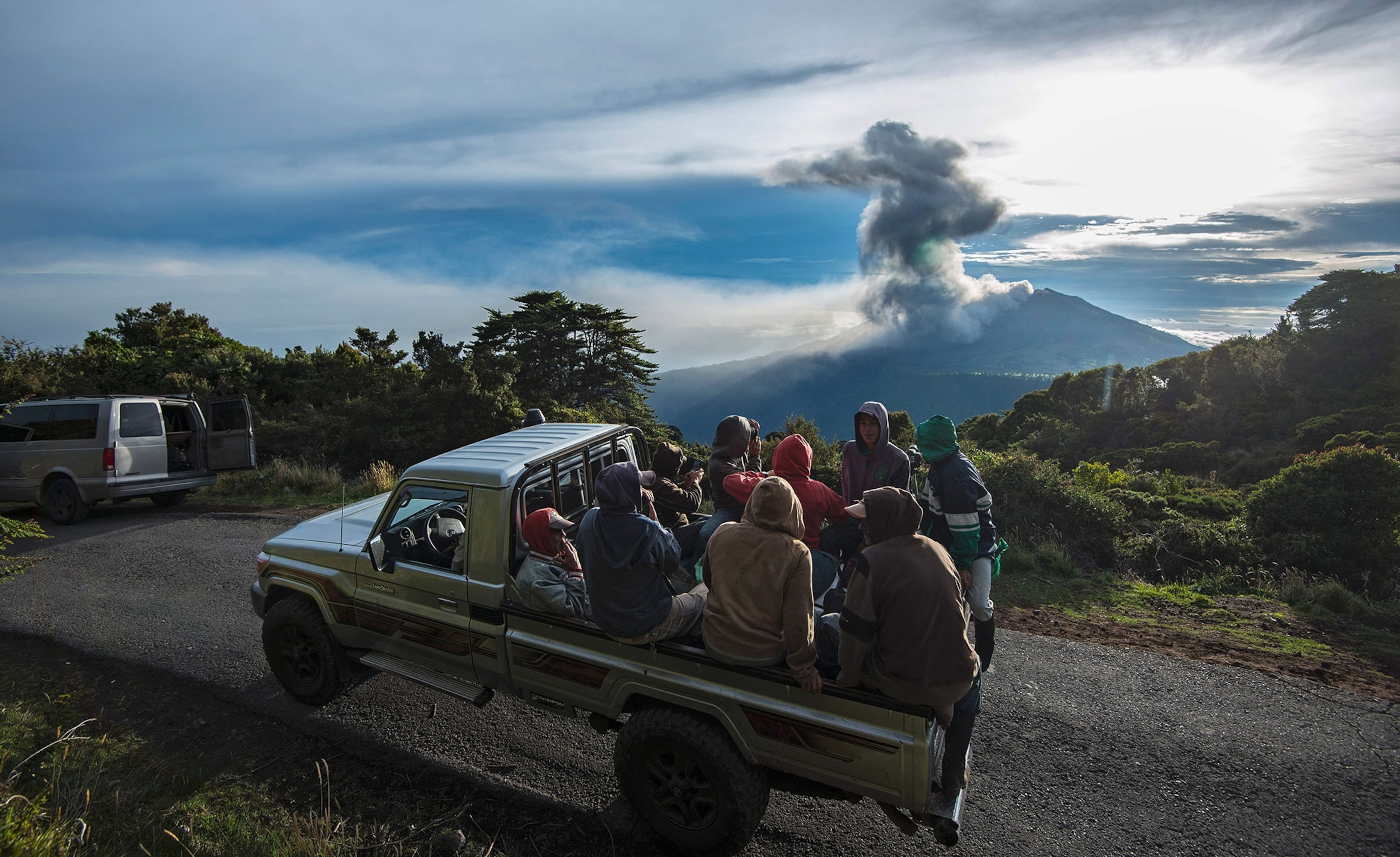 farmers are transported on the back of a truck as the Turrialba volcano erupts