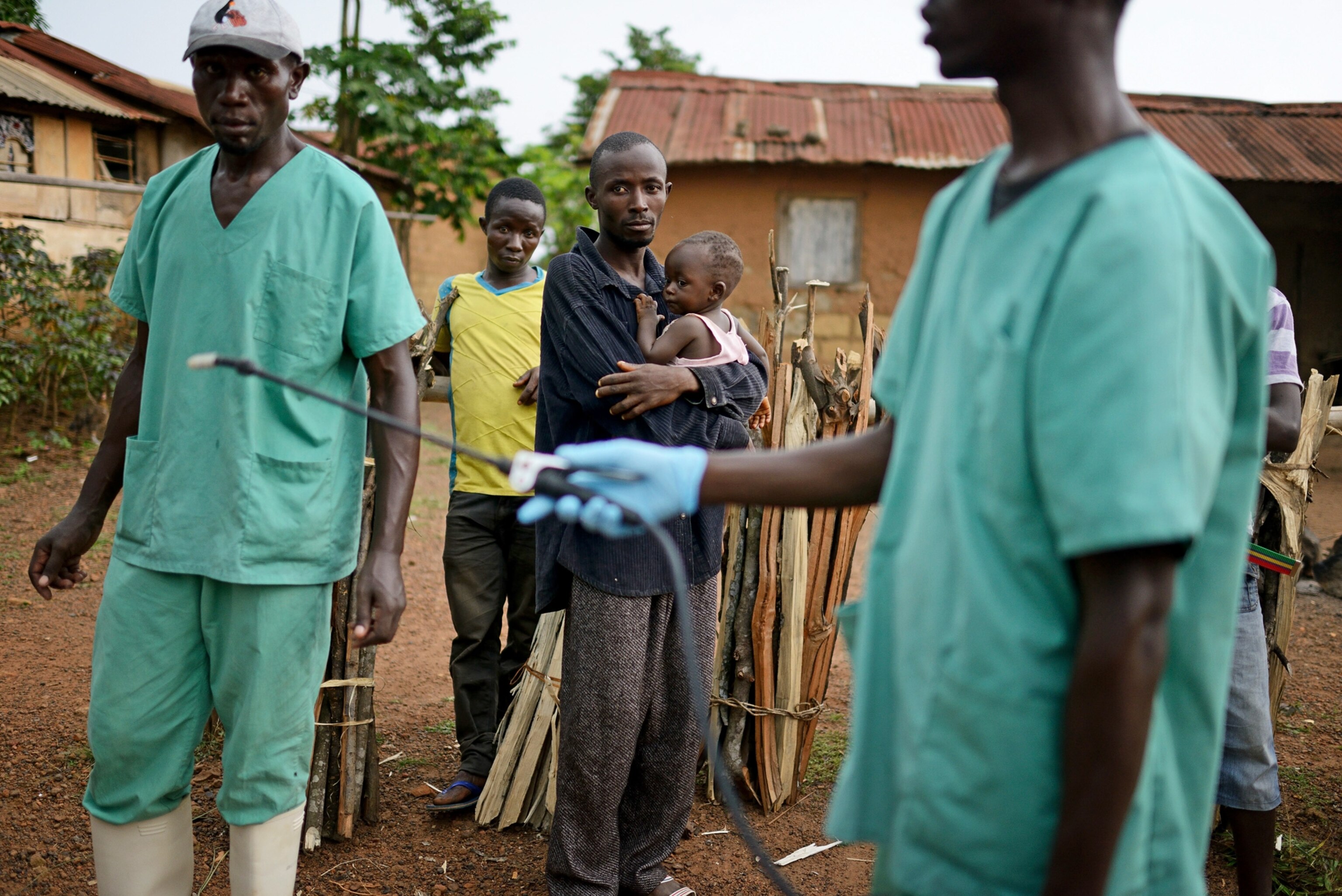 Locals watch workers with Doctors Without Borders as they disinfect after leaving a private clinic.