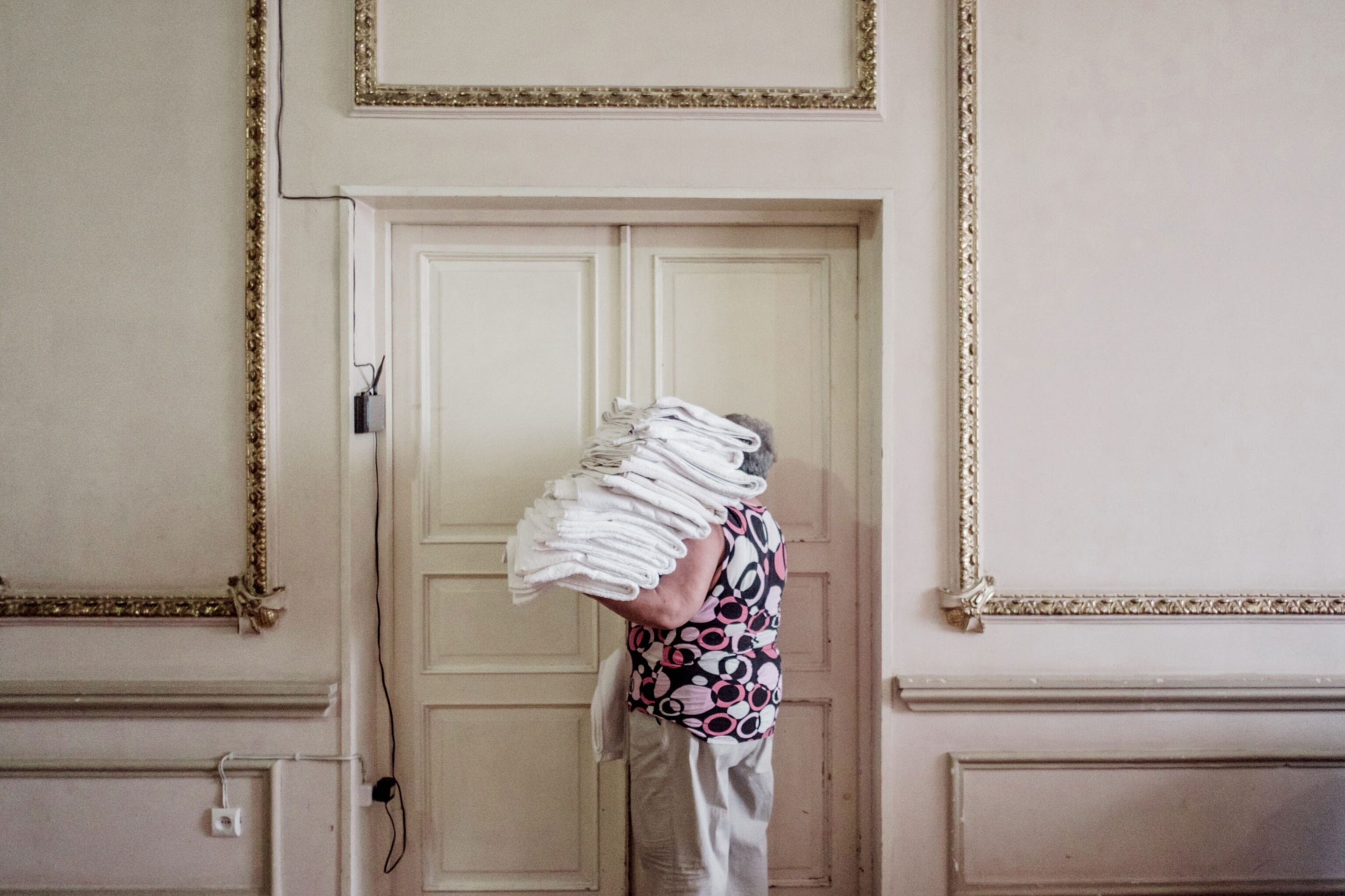 Mzia, 59, carries ironed sheets into the linen closet within Hotel Georgia