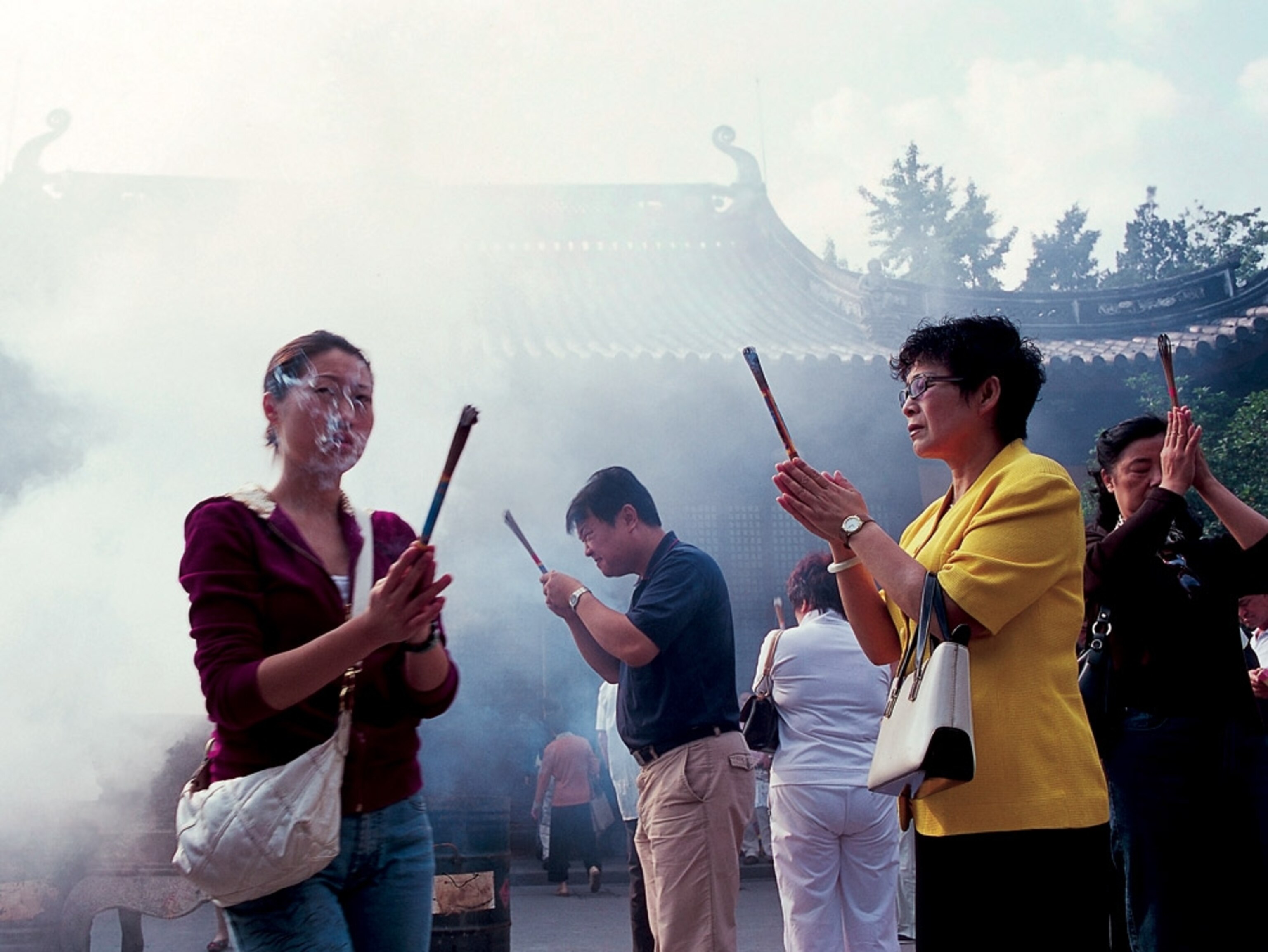 People holding incense at a temple