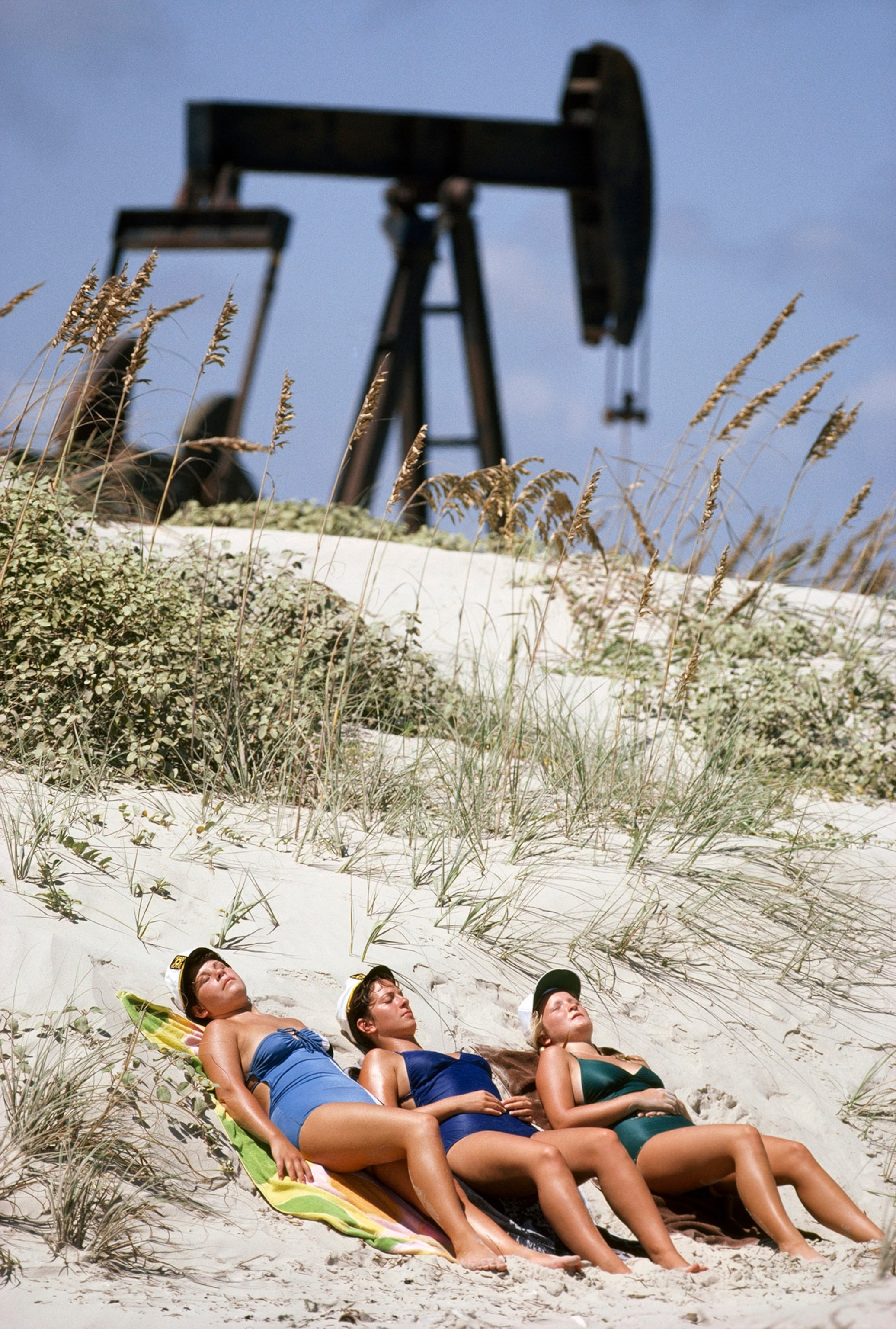 women sunbathing near oil pumps