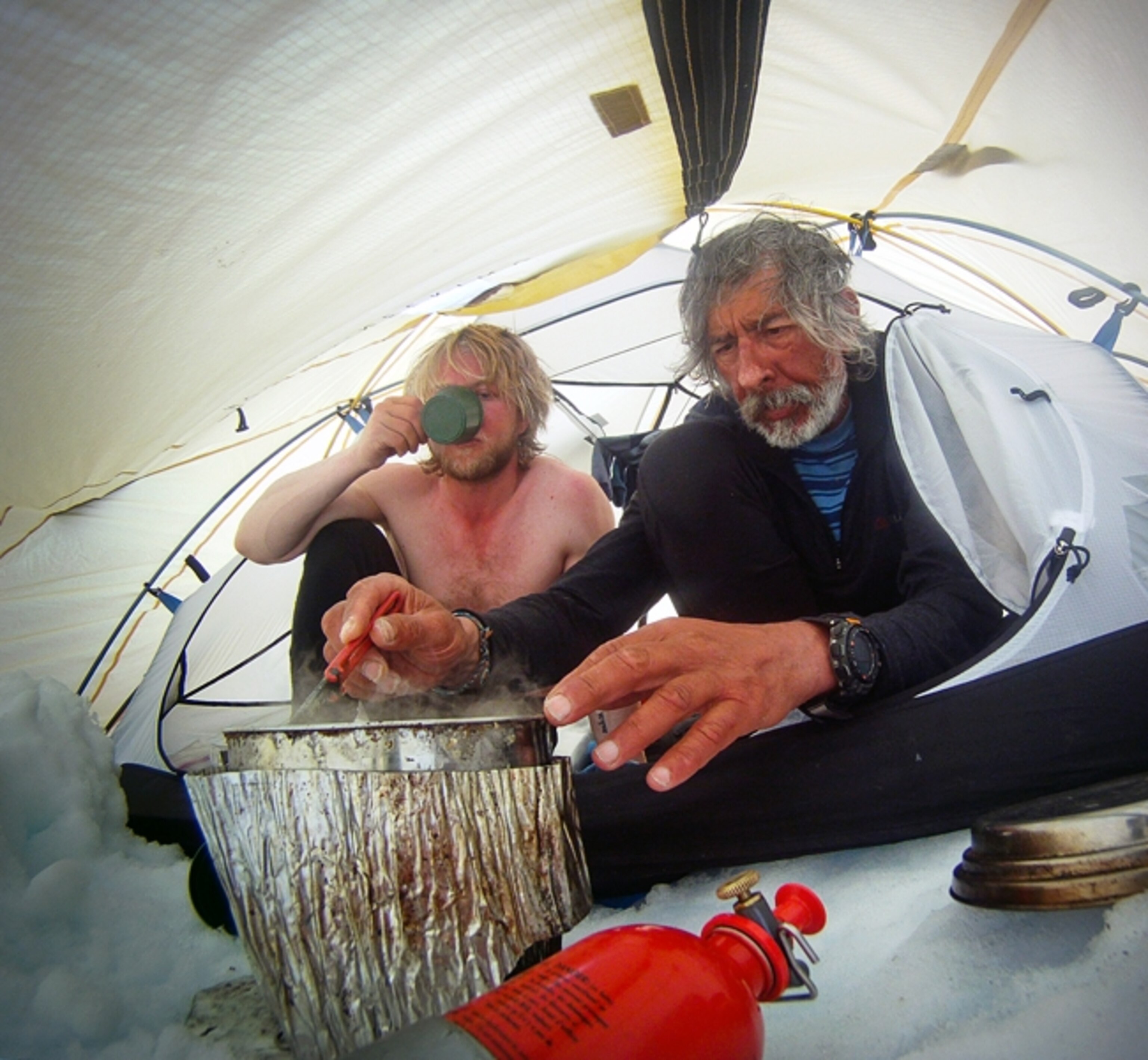 Erik Boomer and Jon Turk rest and eat in camp.