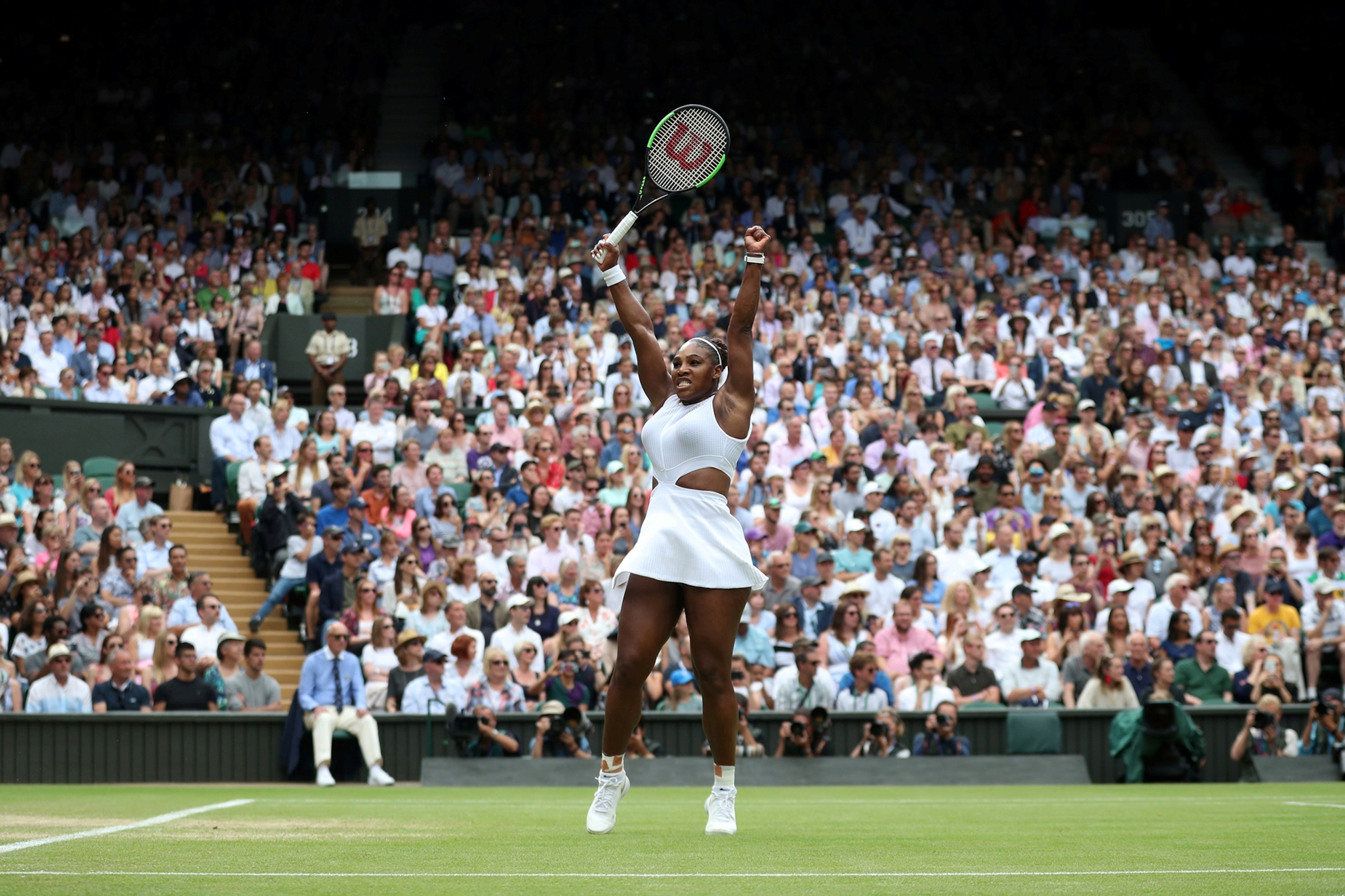 Serena Williams throws her arms up during a tennis match.